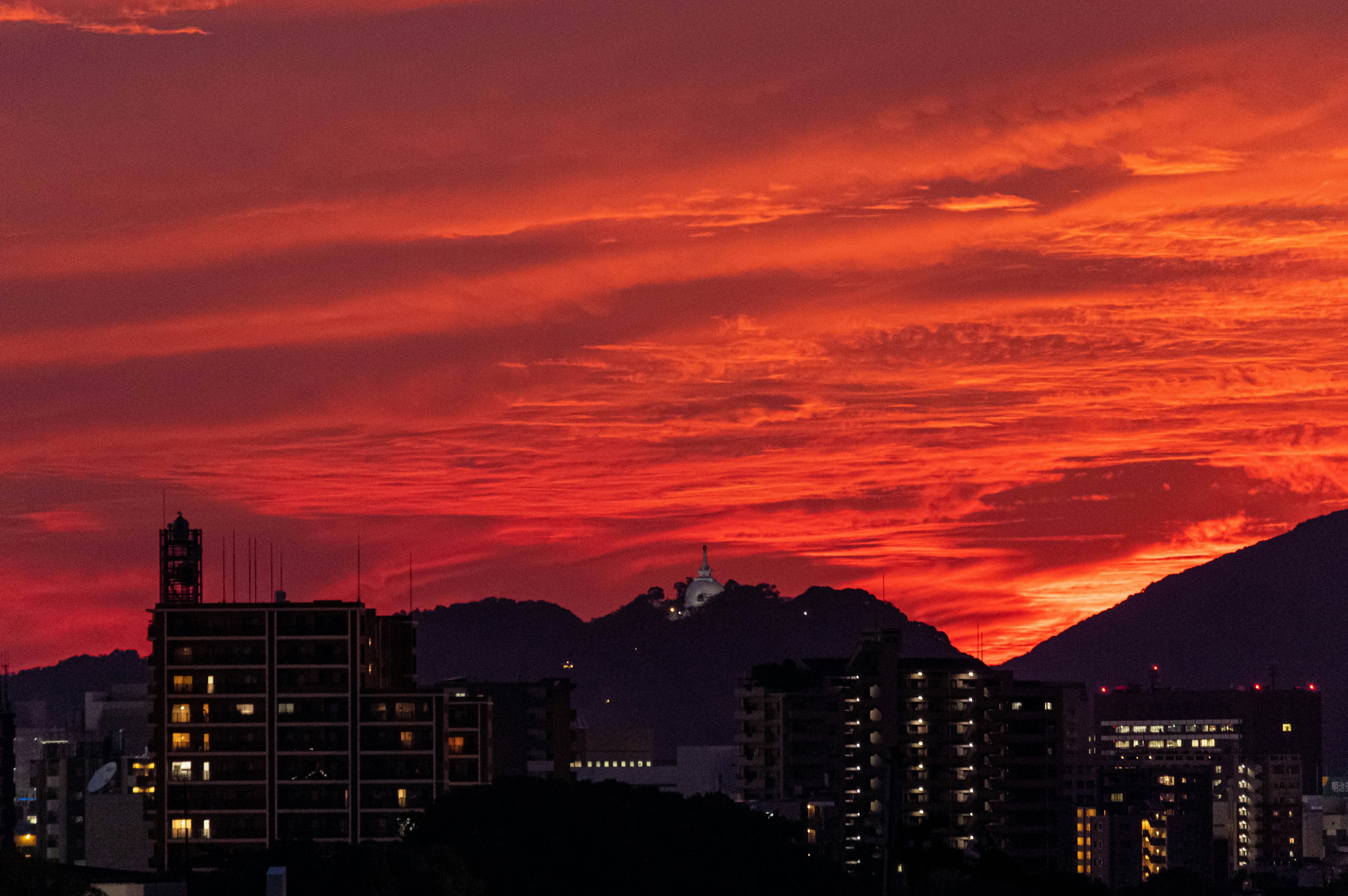 夕焼けの空に映える都市のシルエットと山々