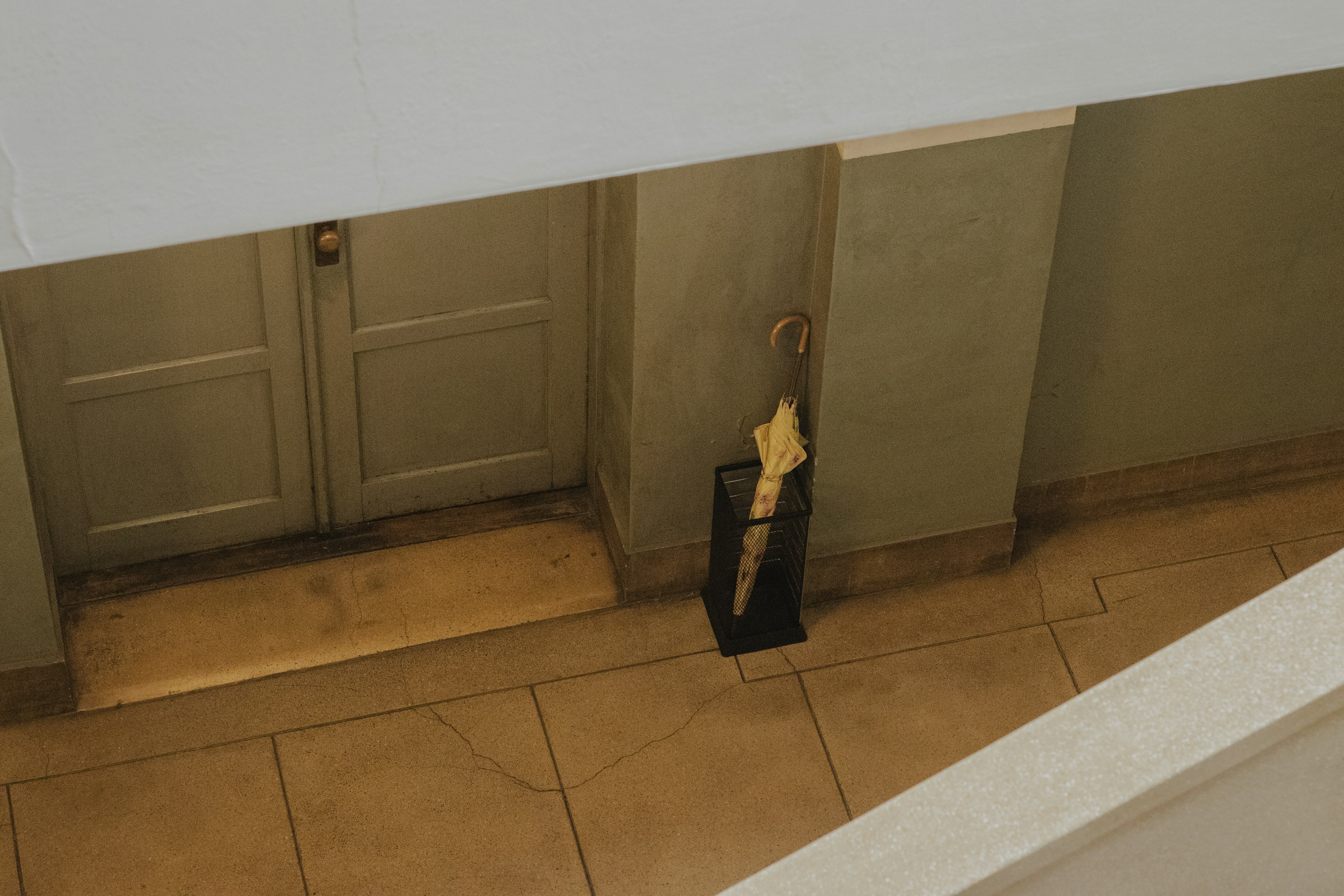 Porte en bois et porte-parapluie décoratif vus d'un escalier