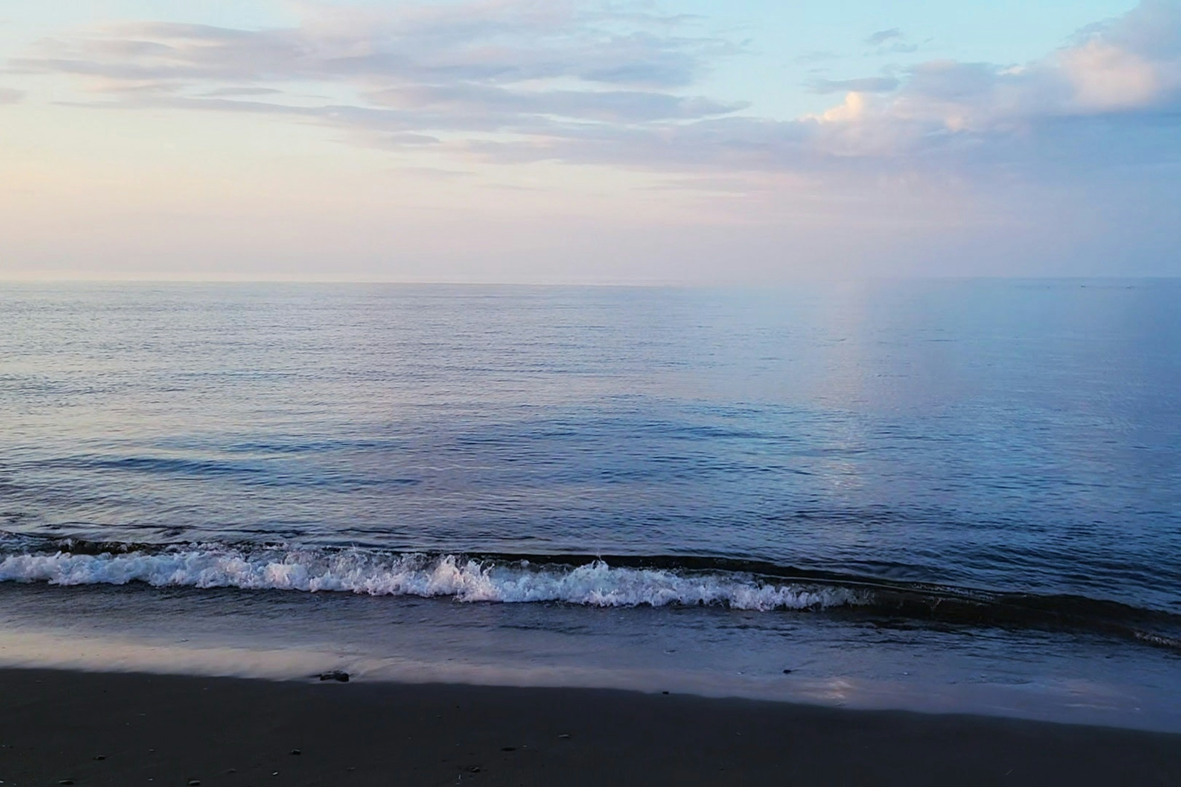 Mare calma con colori tenui del cielo all'alba