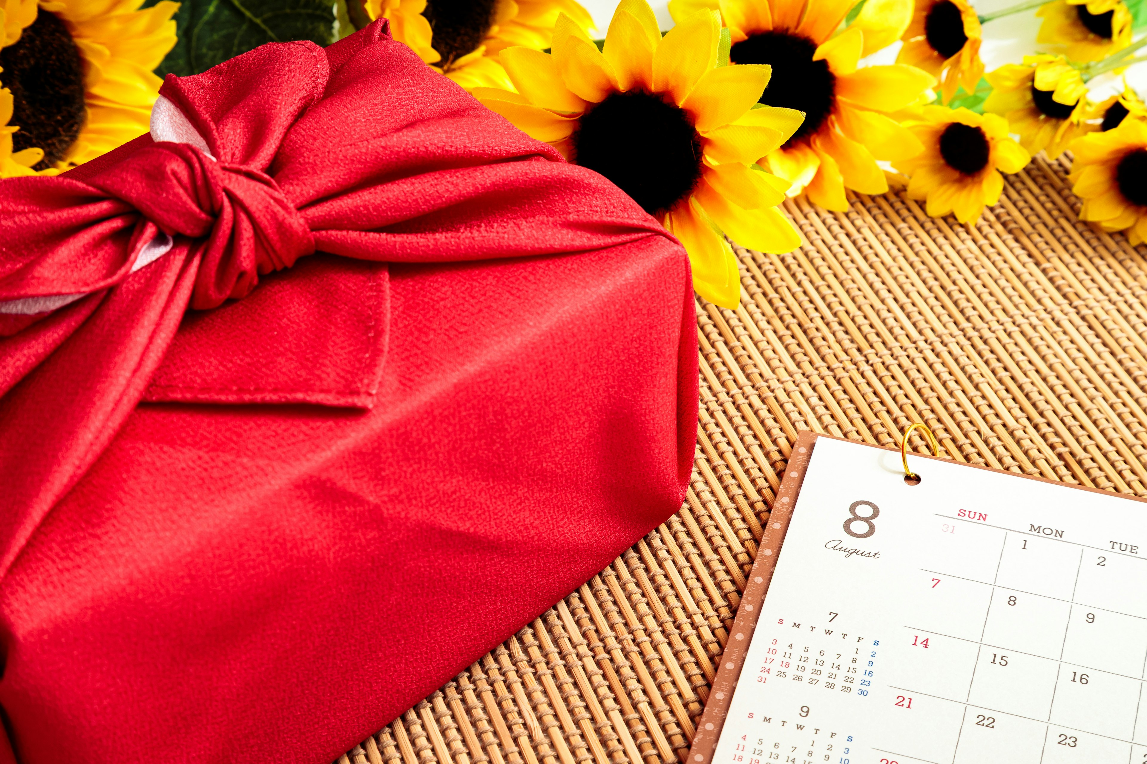 Szene mit einem rot verpackten Geschenk und Sonnenblumen