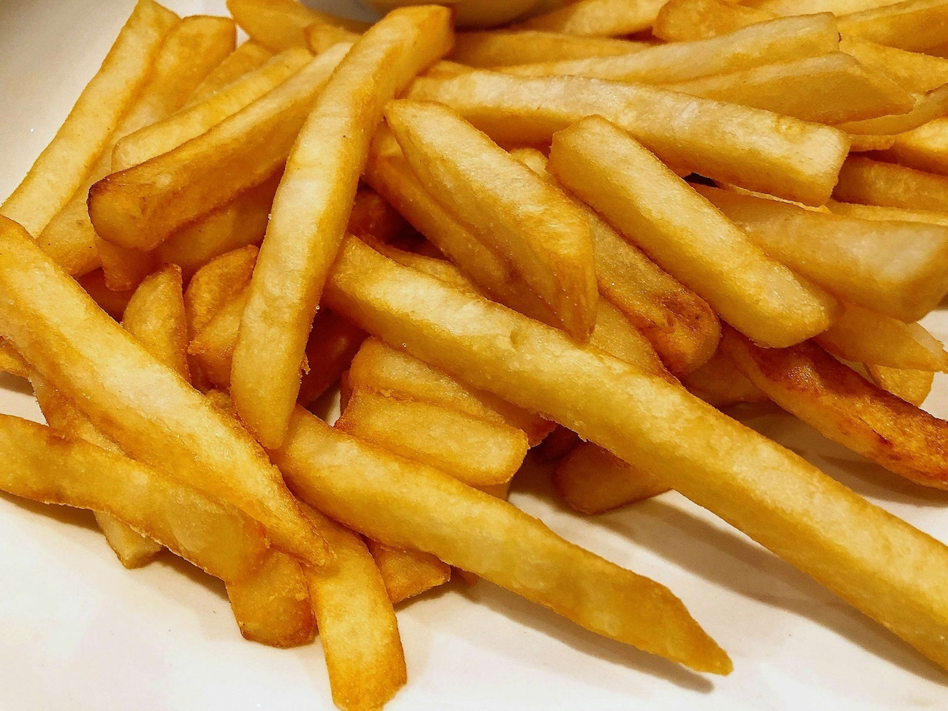 Goldene Pommes frites auf einem Teller gestapelt