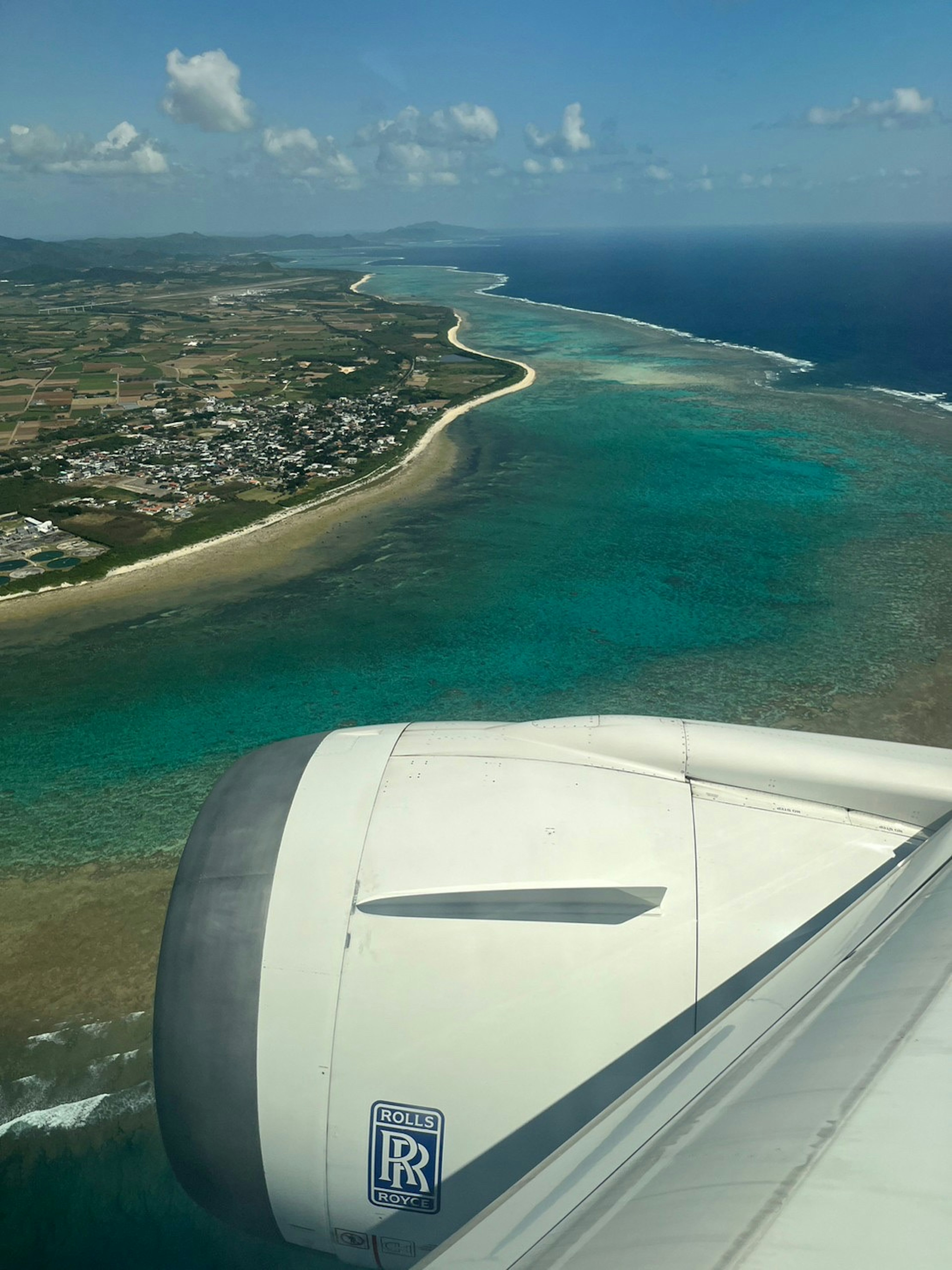 Pemandangan udara perairan turquoise yang hidup dan garis pantai dari sayap pesawat