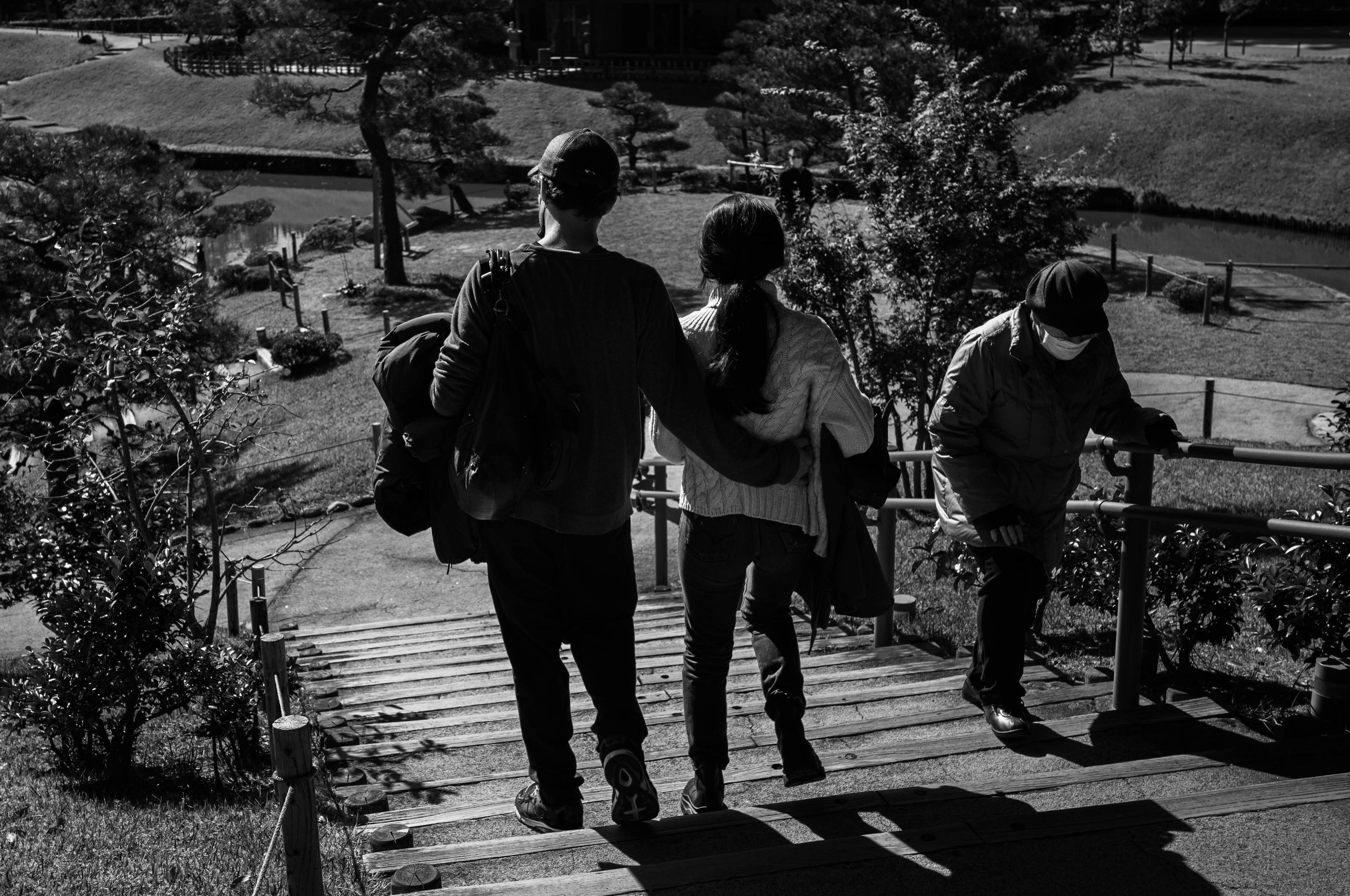 Photo en noir et blanc d'un couple et d'un ami descendant des escaliers