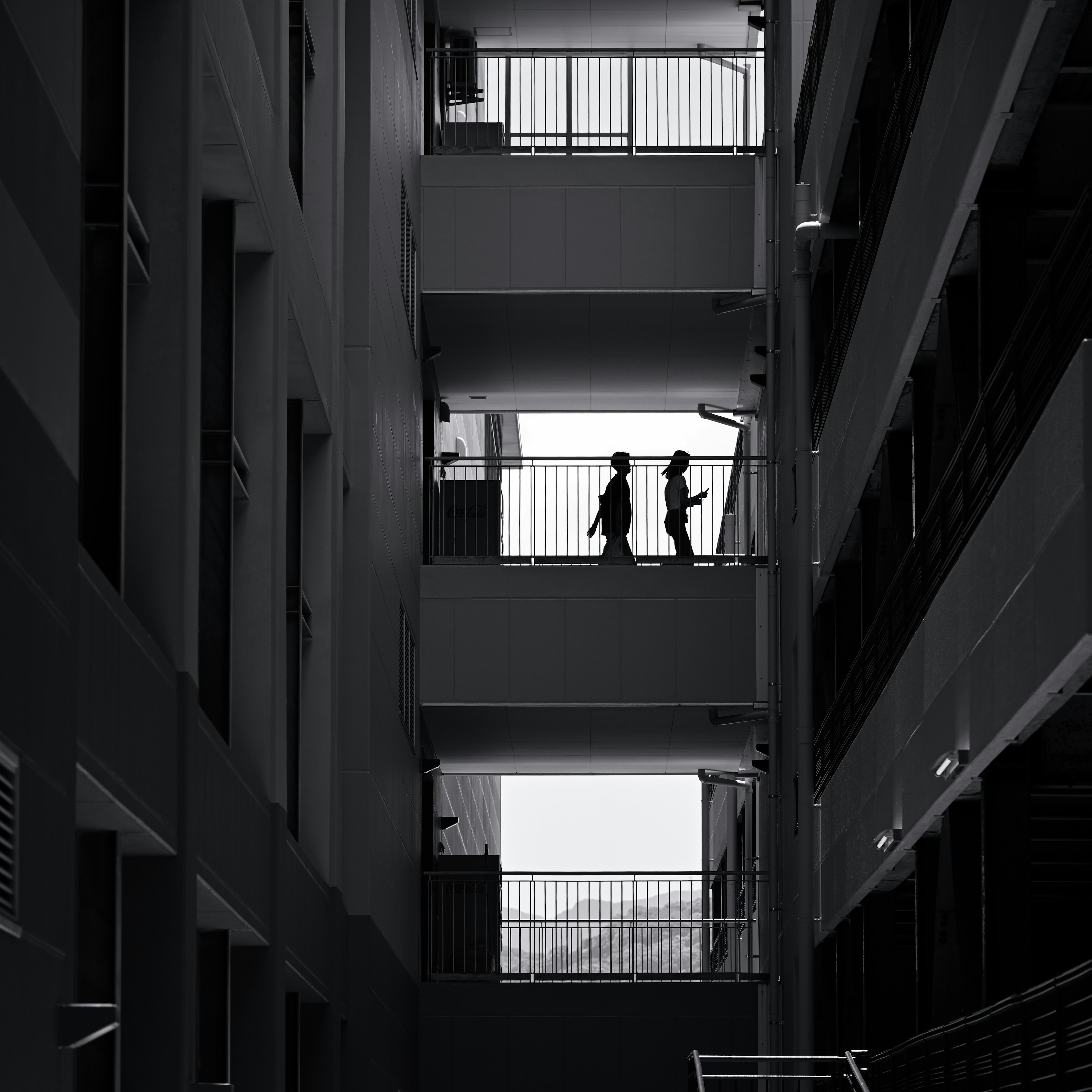 Silhouetten von zwei Personen auf einem Balkon mit monochromer Gebäudearchitektur