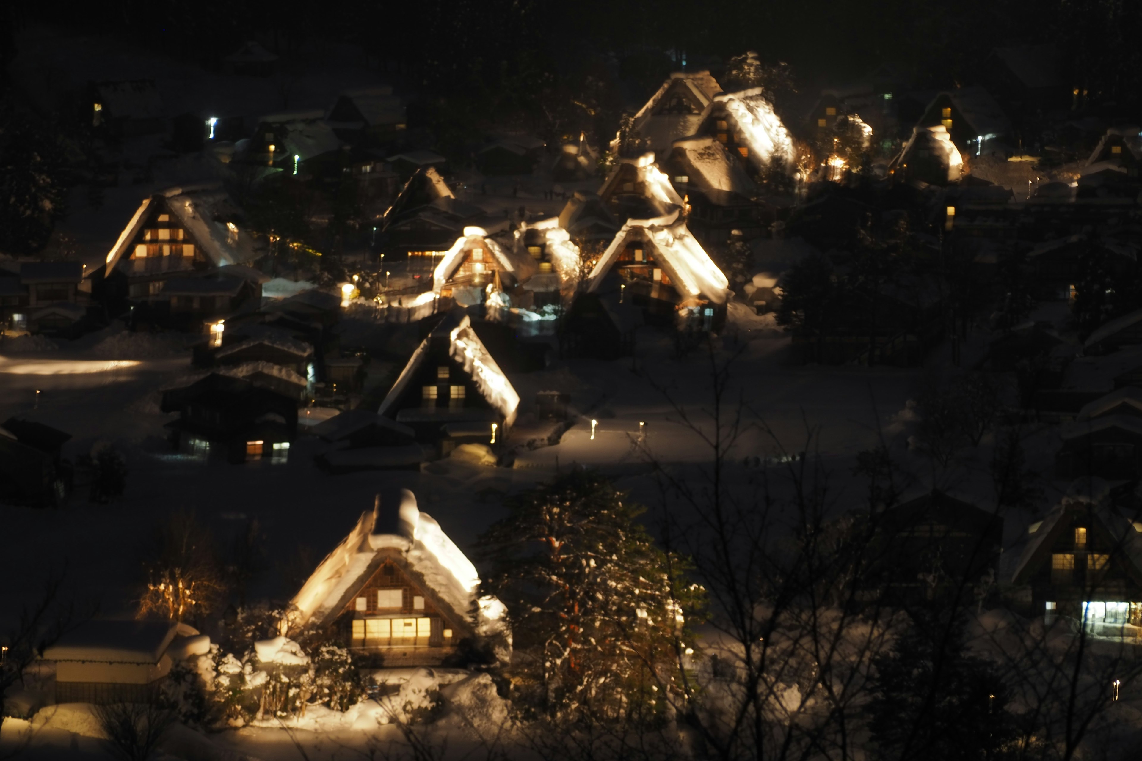 Snow-covered village at night traditional gassho-zukuri houses illuminated with warm lights