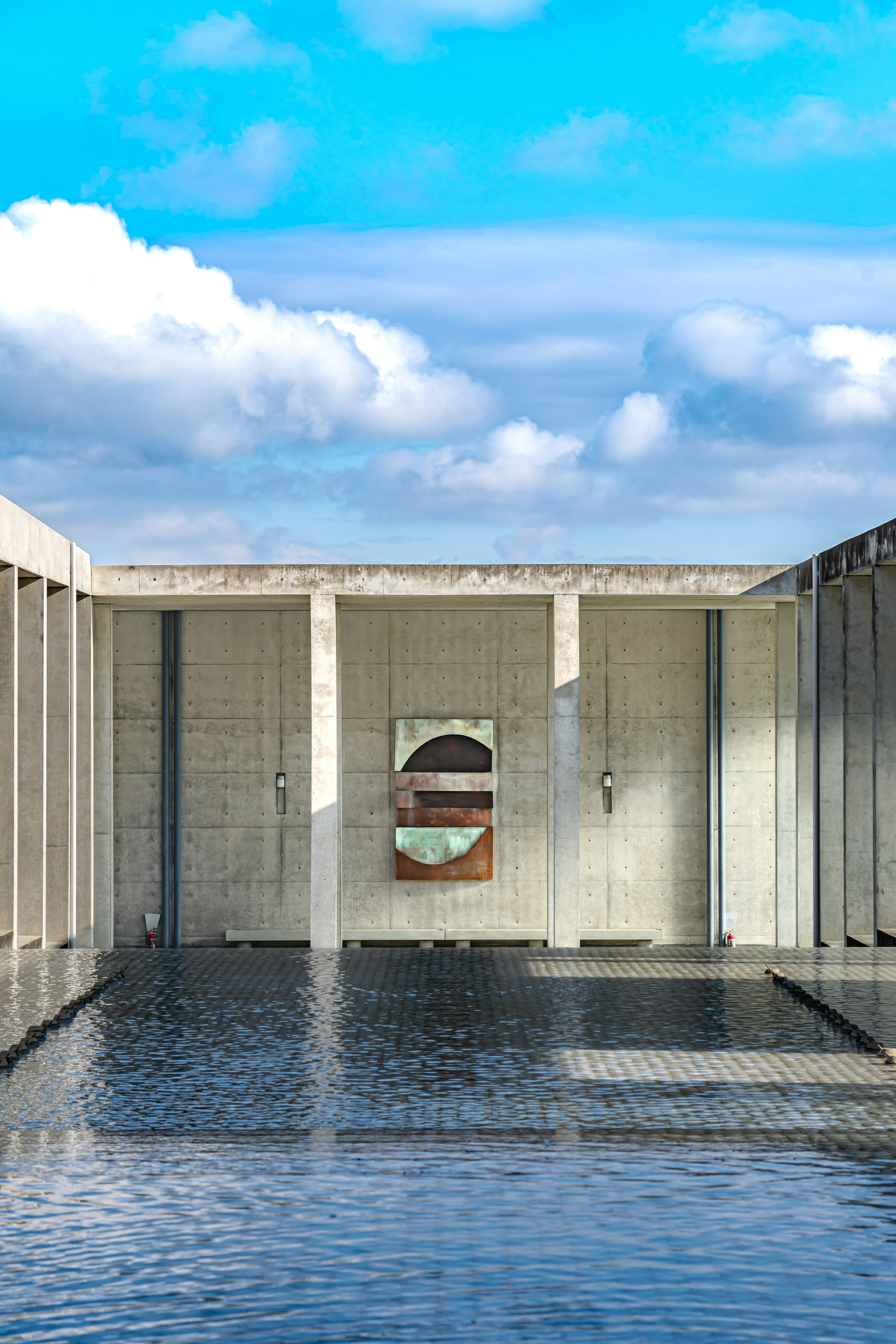 Concrete structure reflecting on water with a blue sky