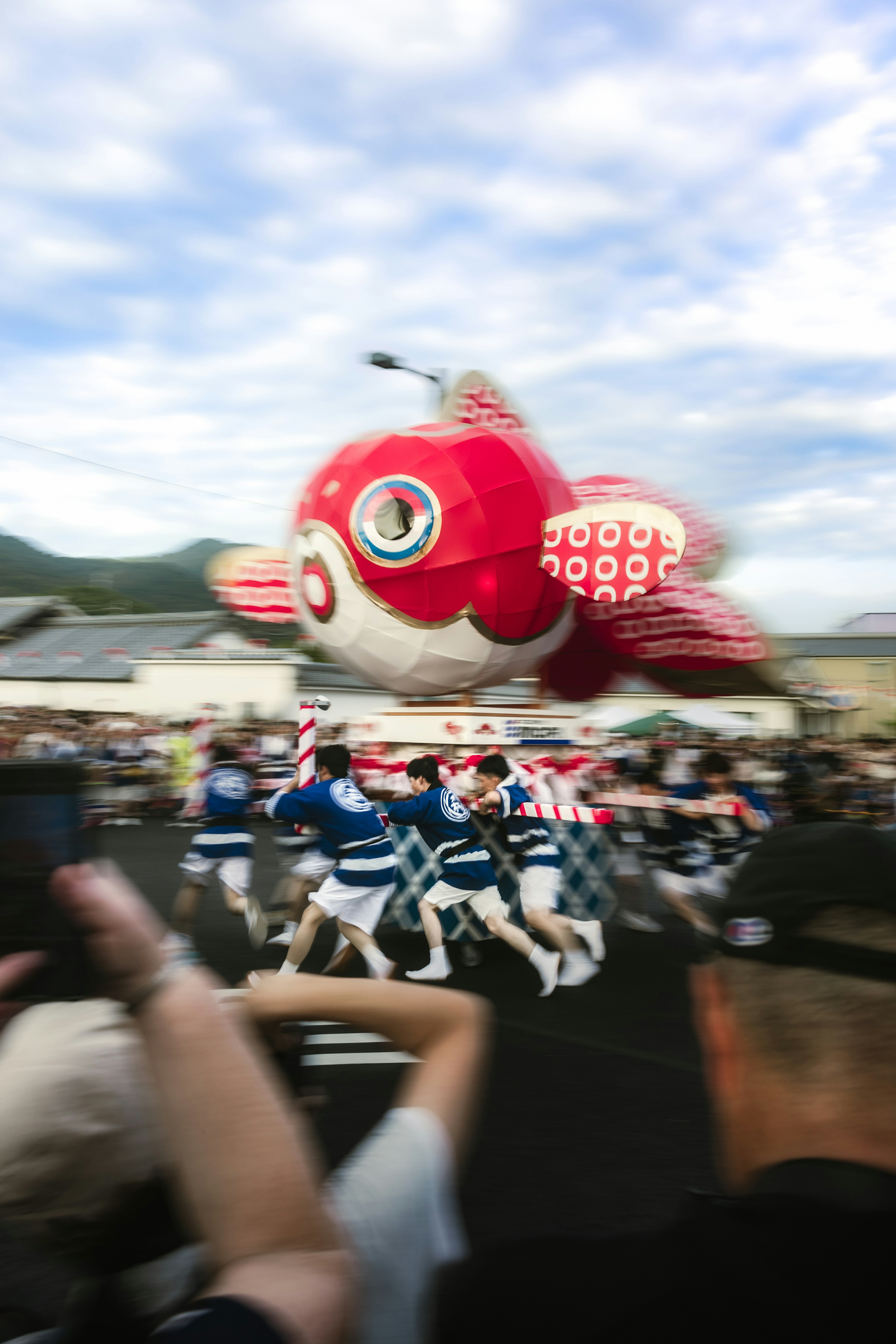 赤い金魚の風船が祭りで浮かんでいる周りに踊る人々