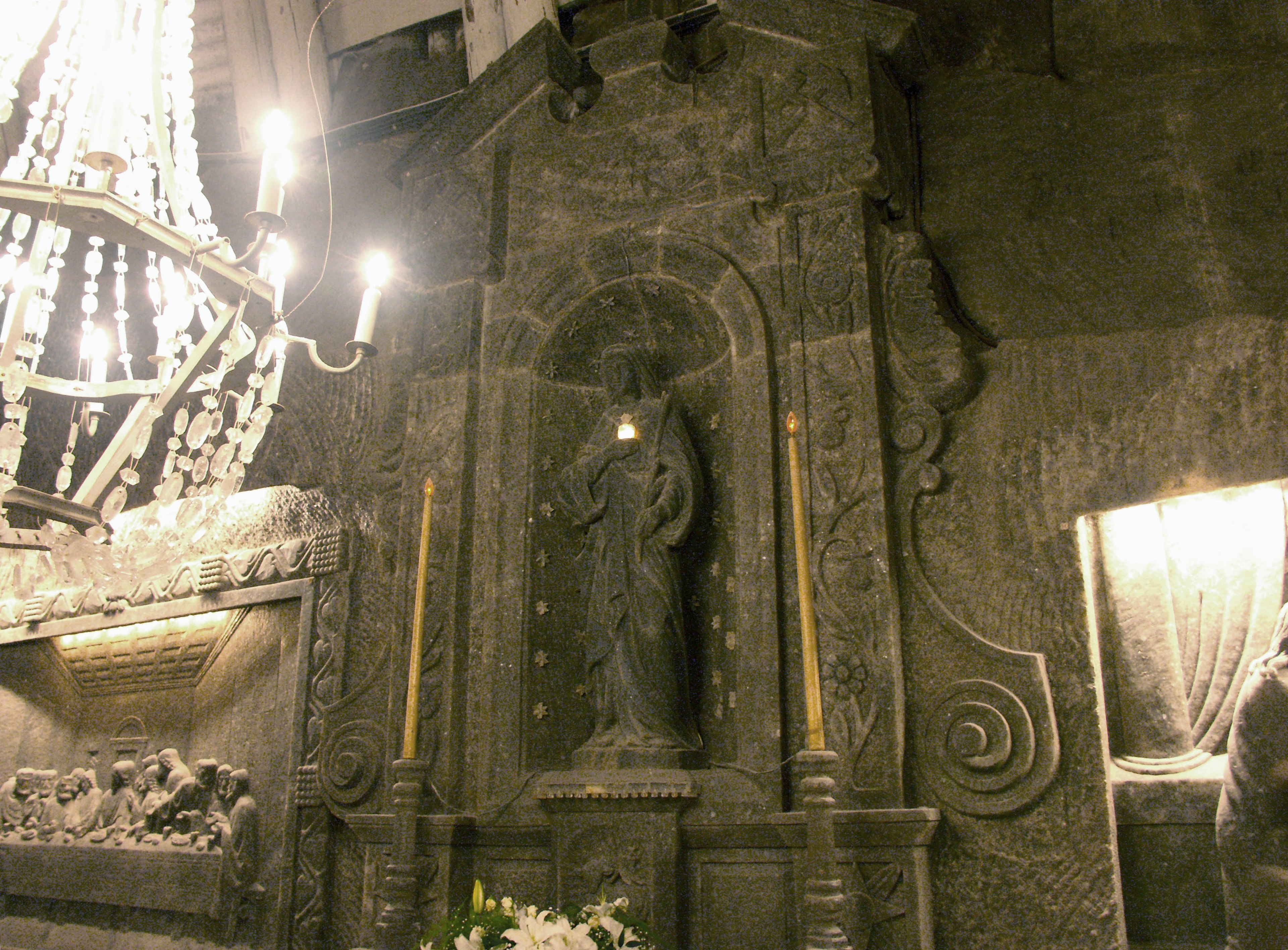 Interior of an underground church featuring a statue and a chandelier