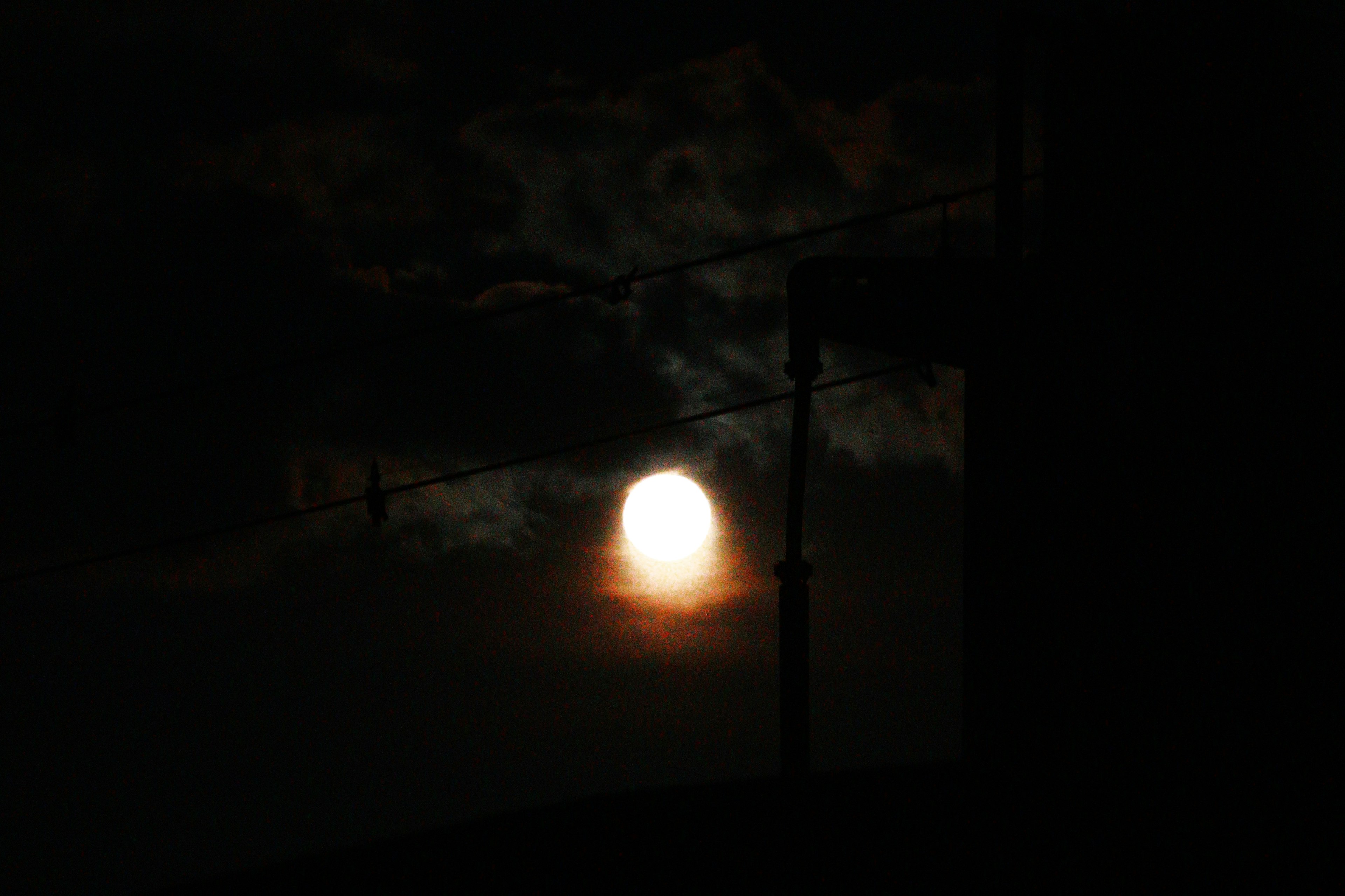 Bright moon shining through dark clouds at night