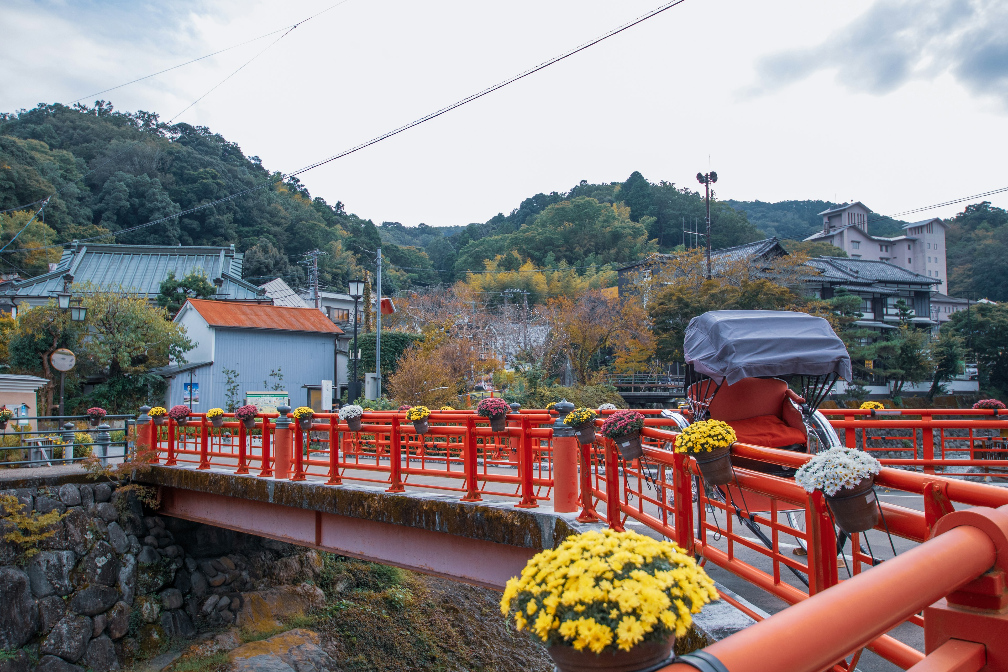 Pont rouge entouré de montagnes avec des décorations florales sur les rampes