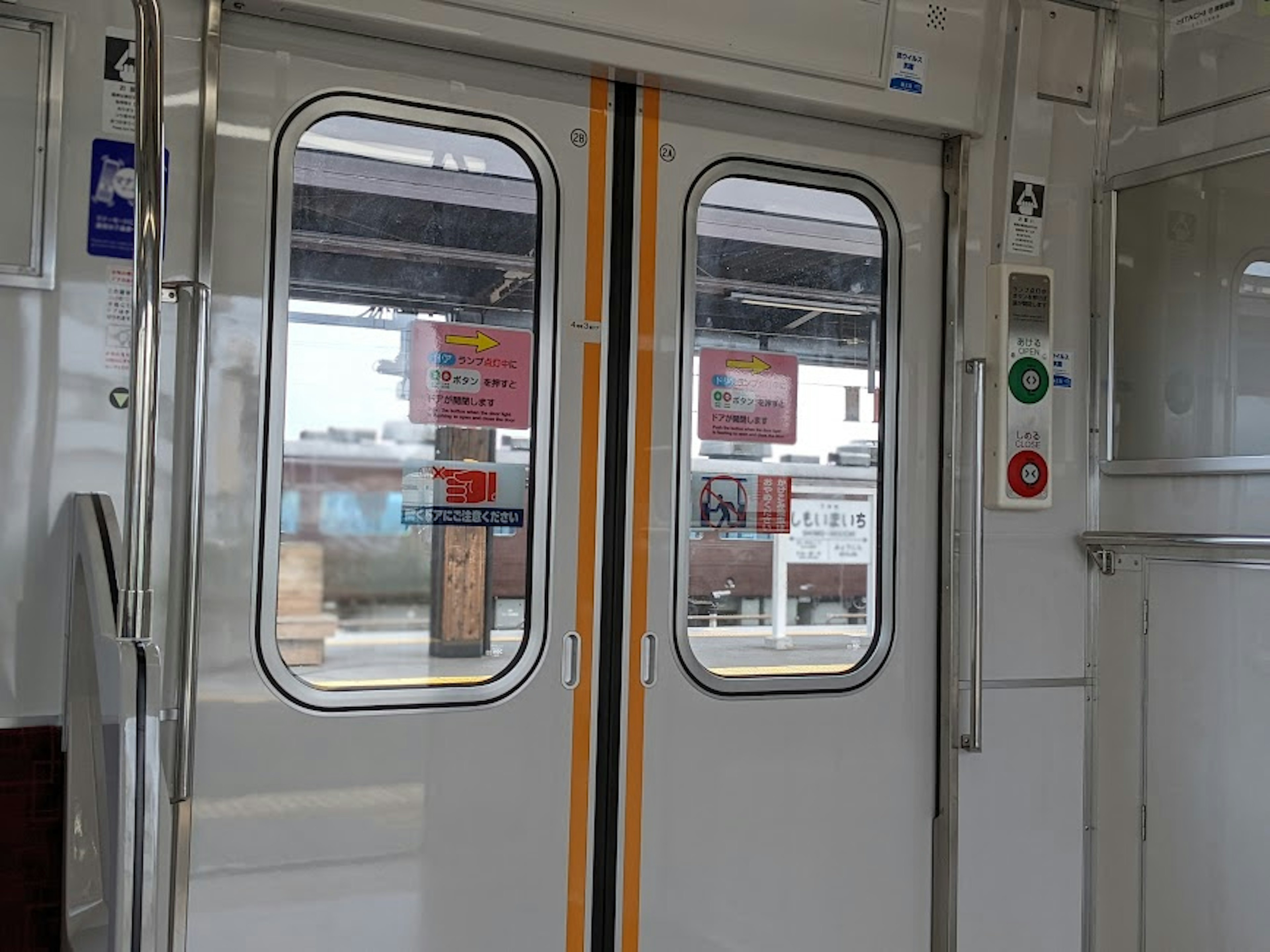 Interior view of train doors with buttons and station signs