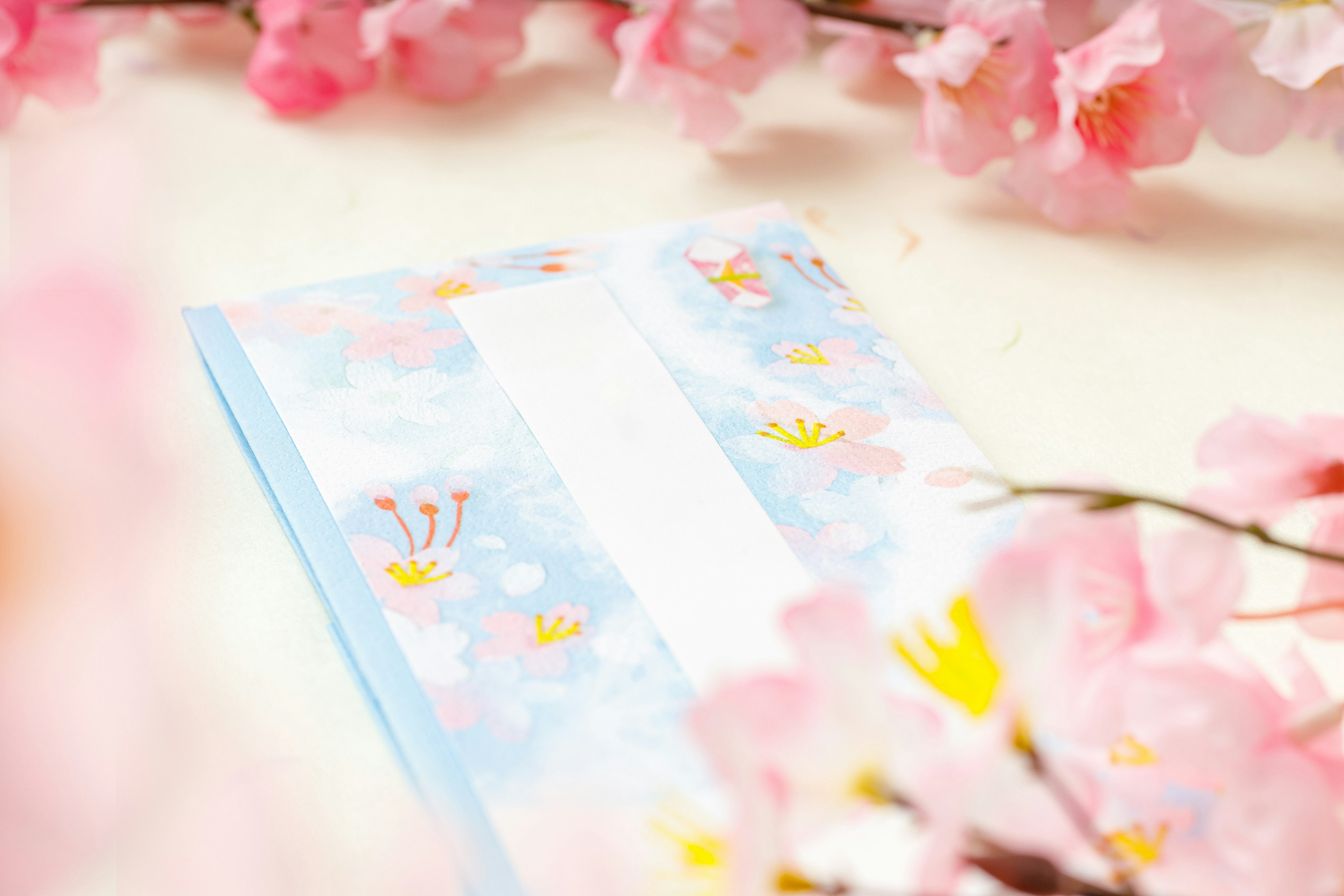 Blue envelope surrounded by pink cherry blossom petals with colorful design