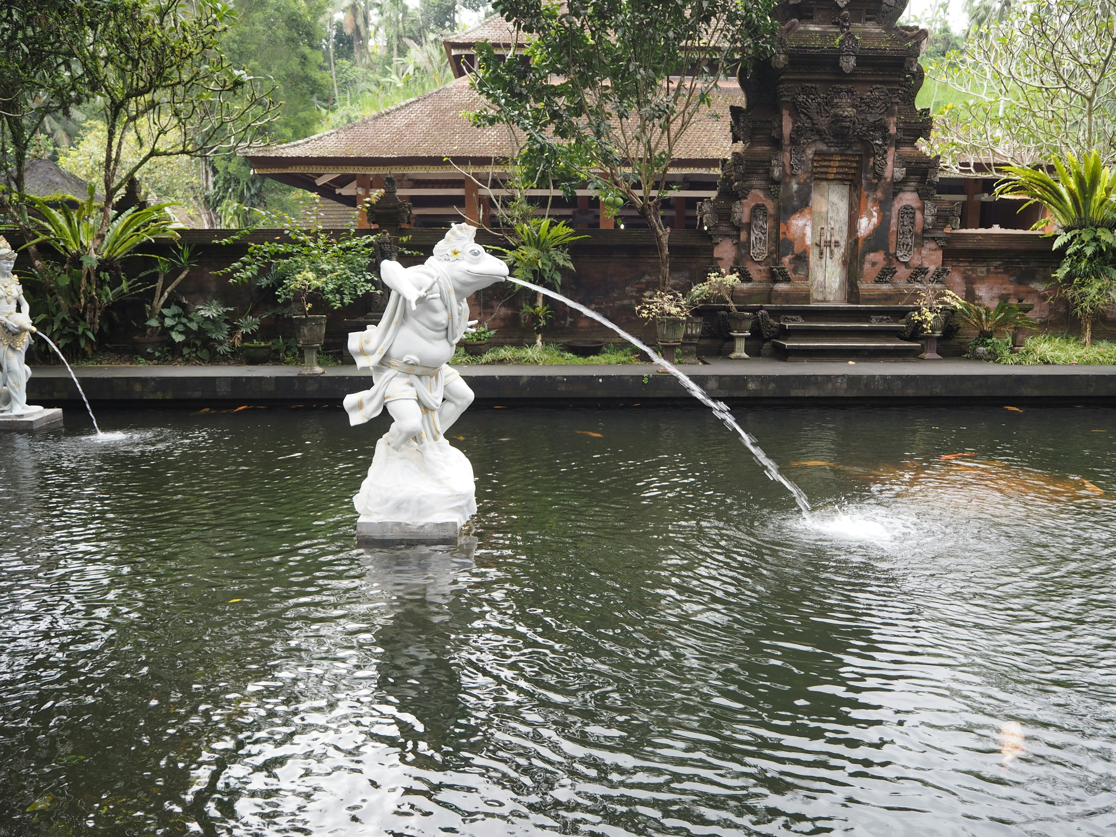 バリの伝統的な彫刻がある池の風景 水が彫刻から噴き出している