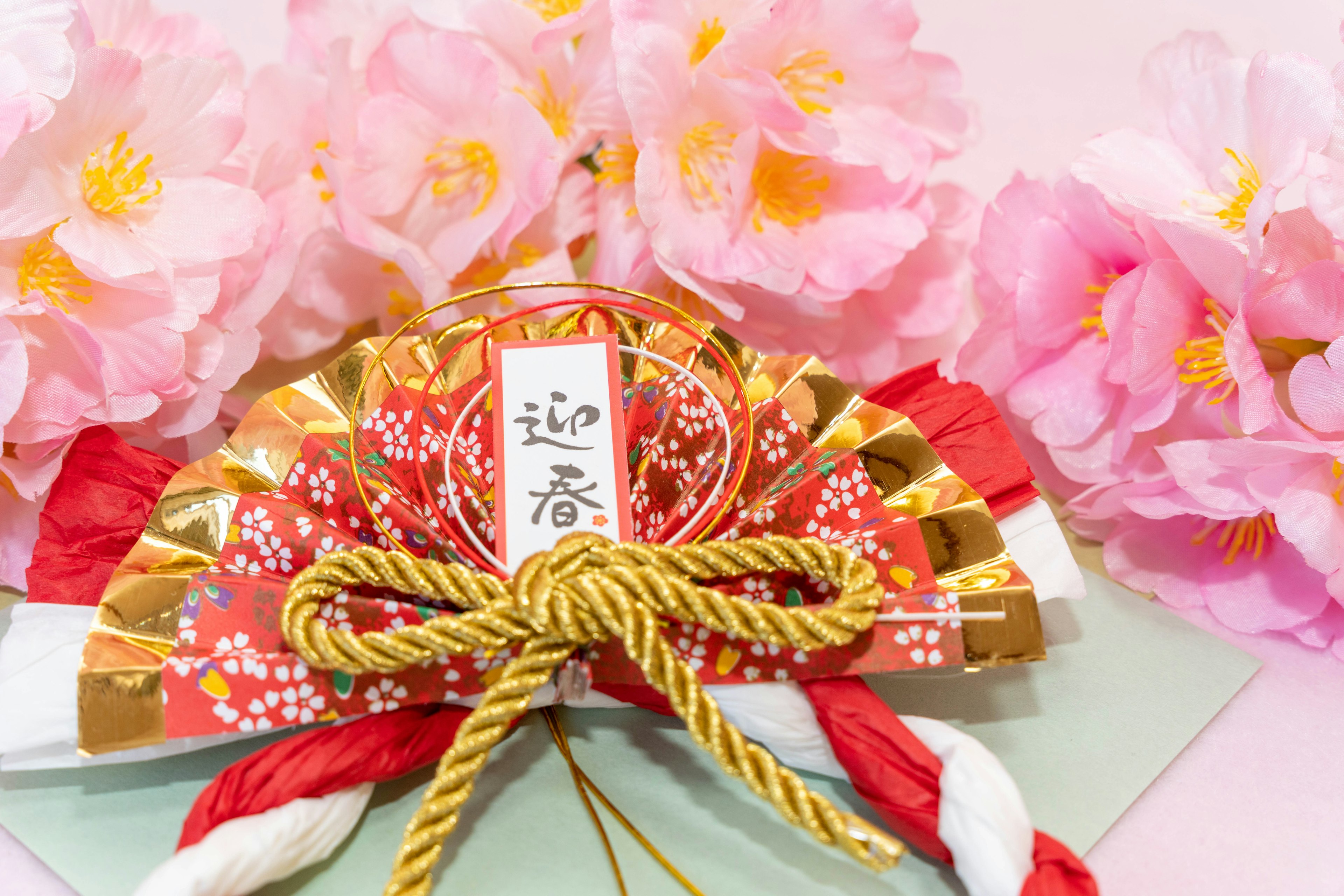 Traditional Japanese decoration with gold ribbon in front of cherry blossoms