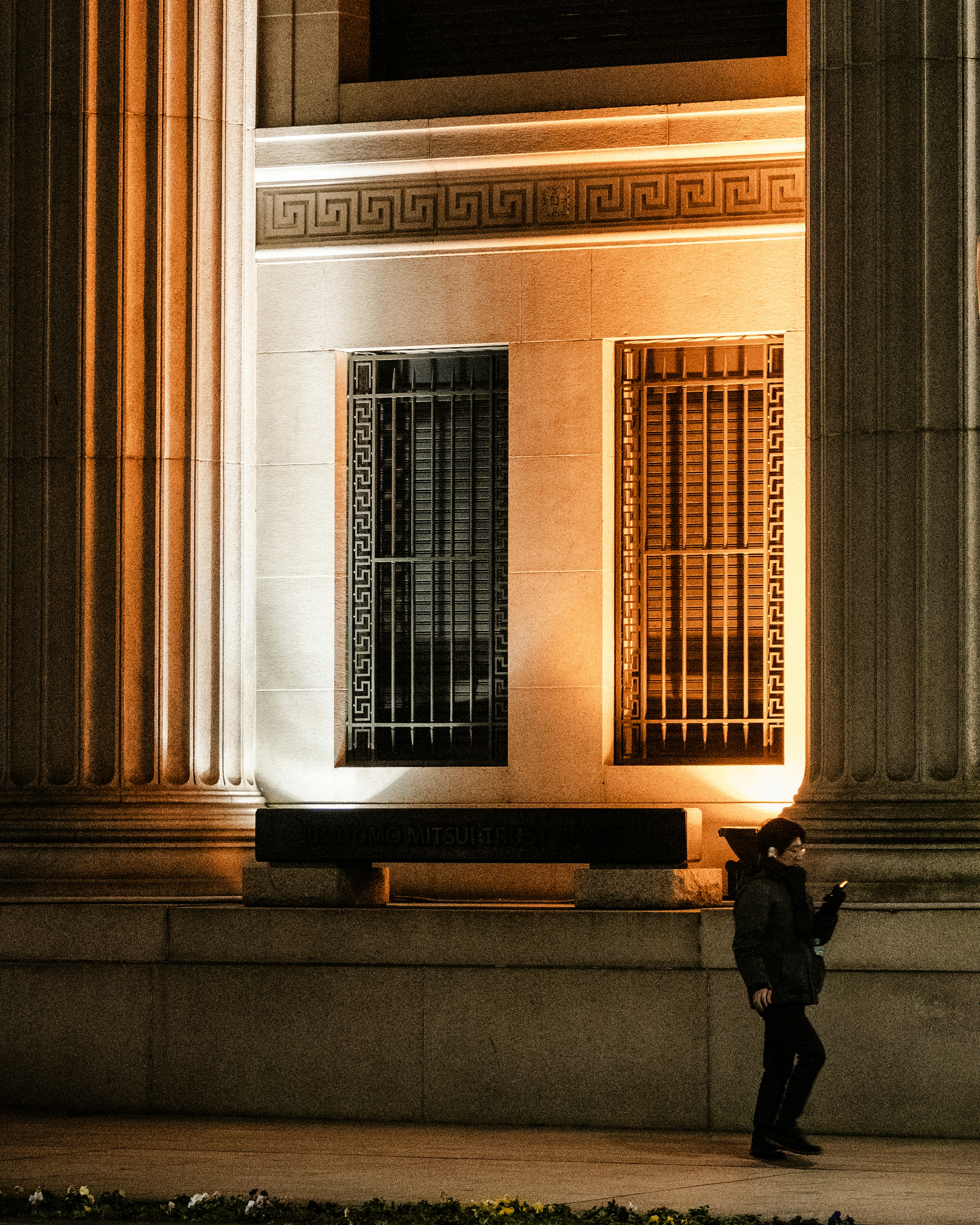 Person standing beside a building at night with illuminated columns