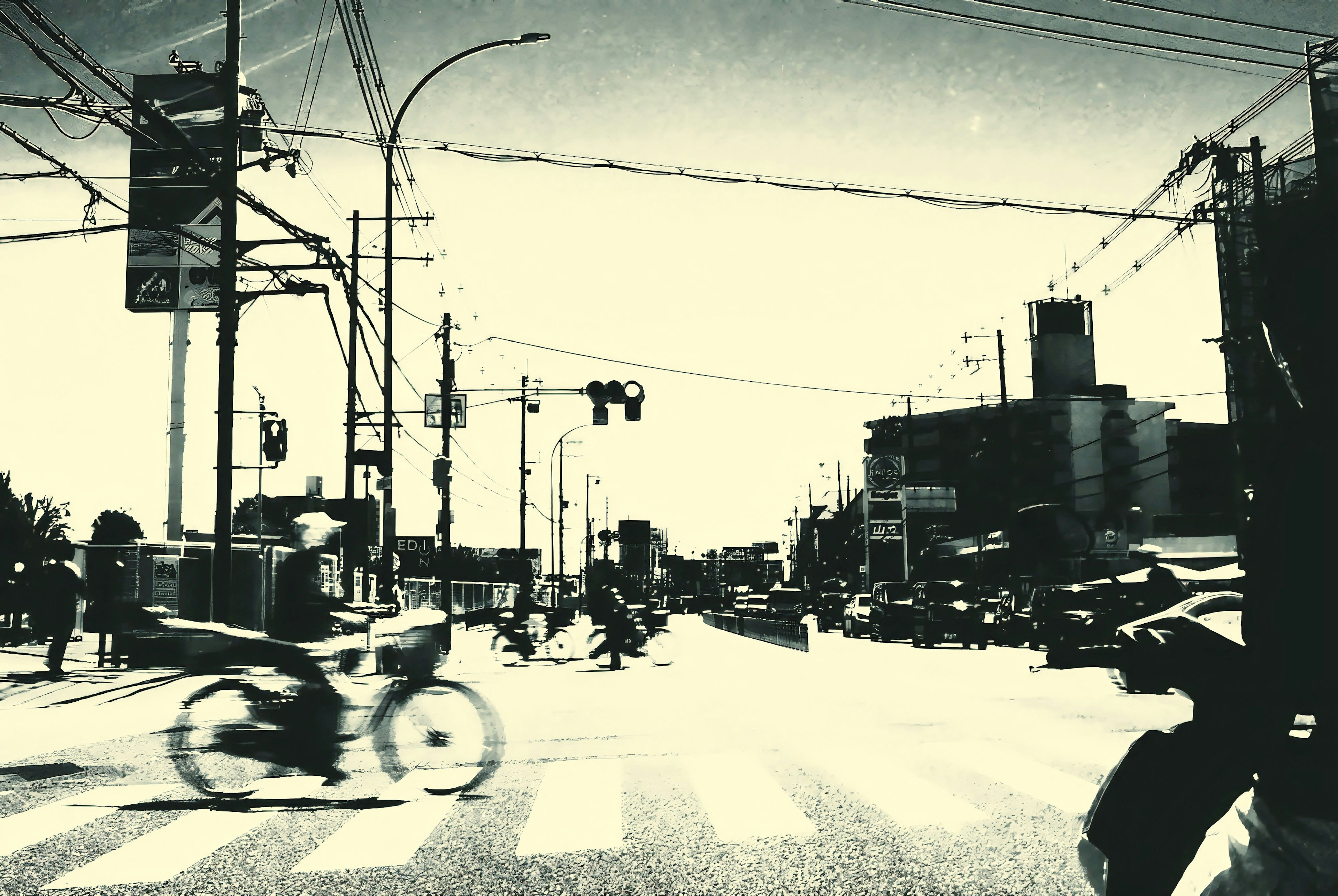 Black and white street corner view of an intersection with passing bicycles and cars prominent traffic lights and street lamps