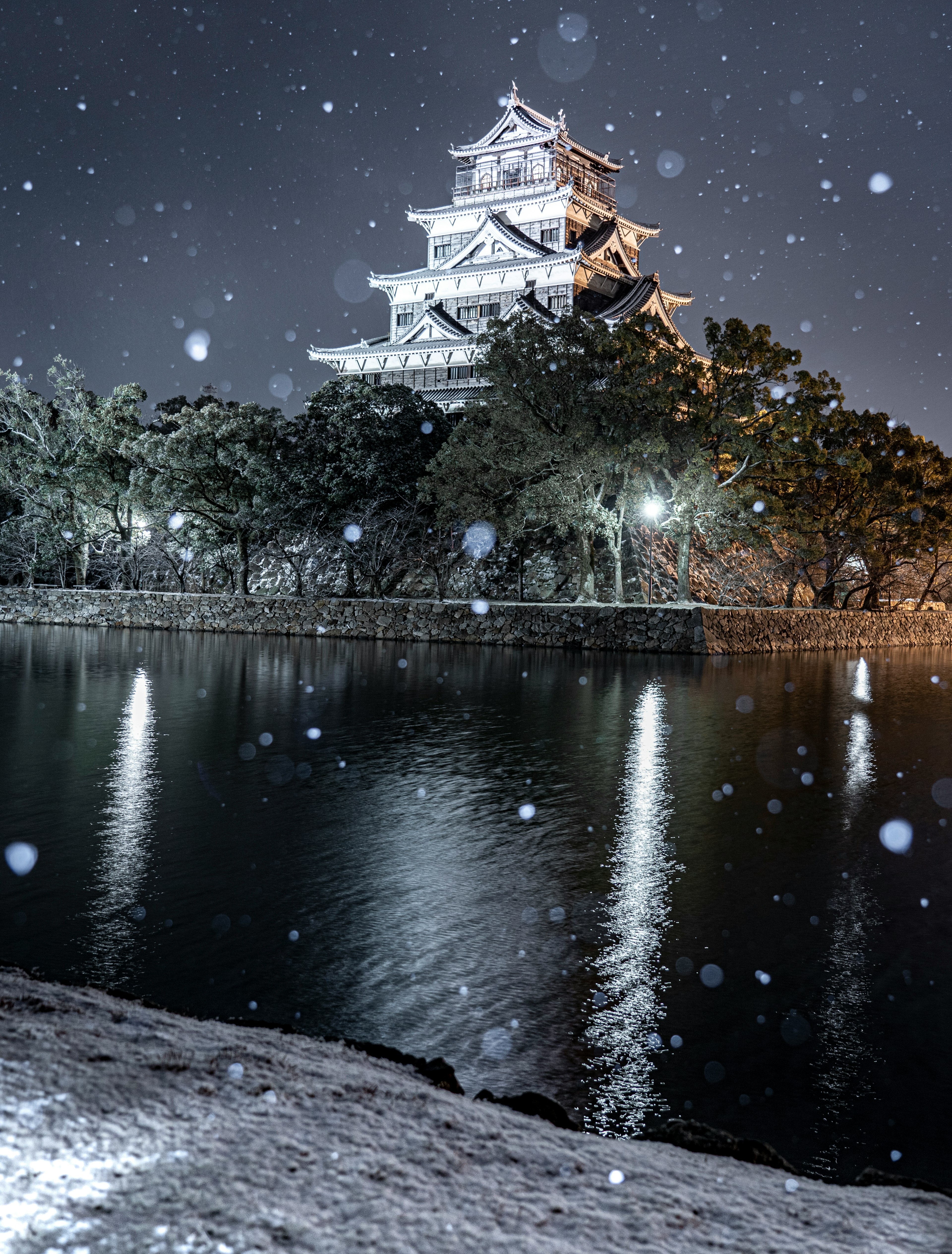 Escena nocturna nevada de un castillo con reflejos en el agua