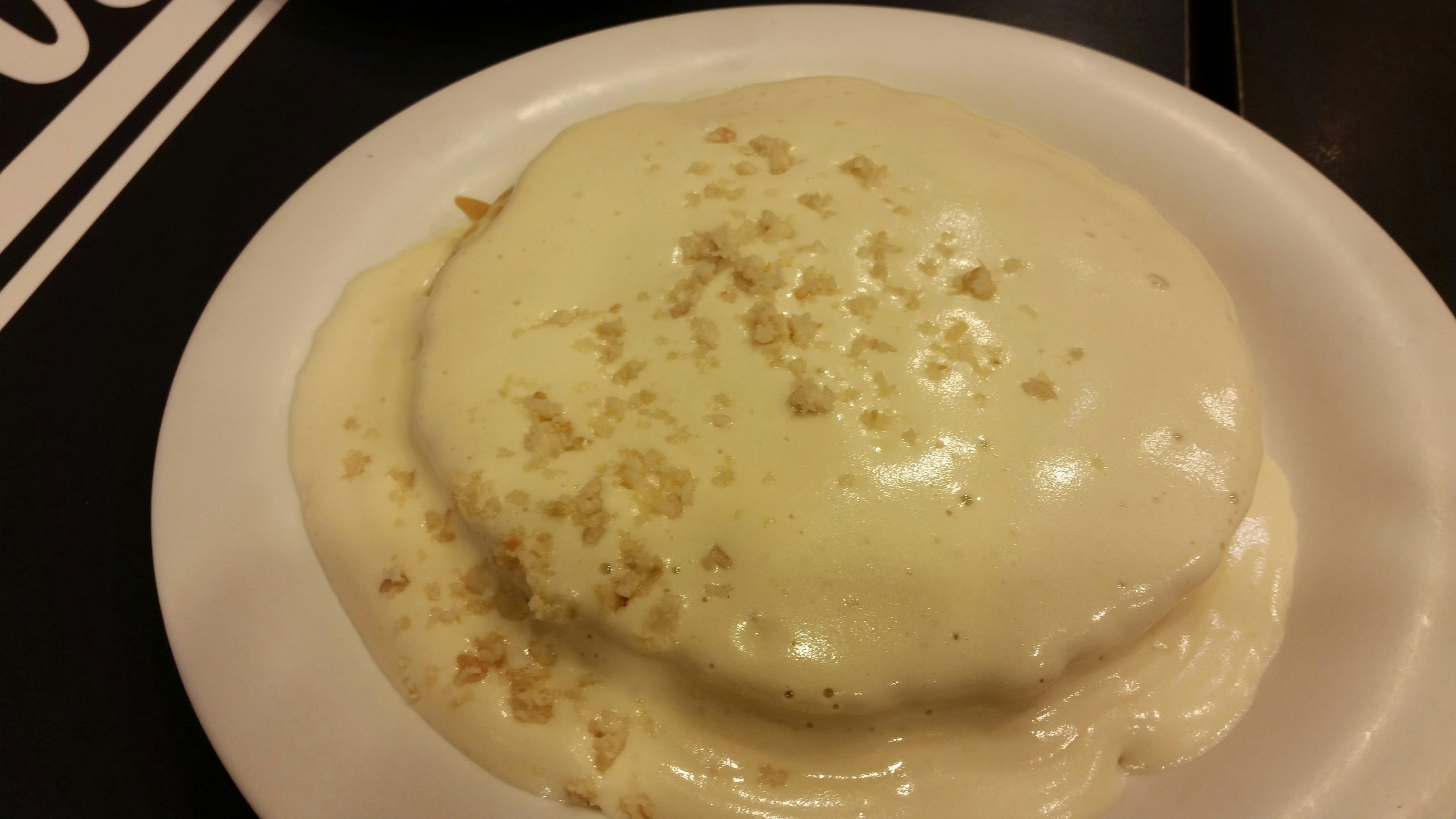 Plate of pancakes topped with creamy white sauce and crumbs