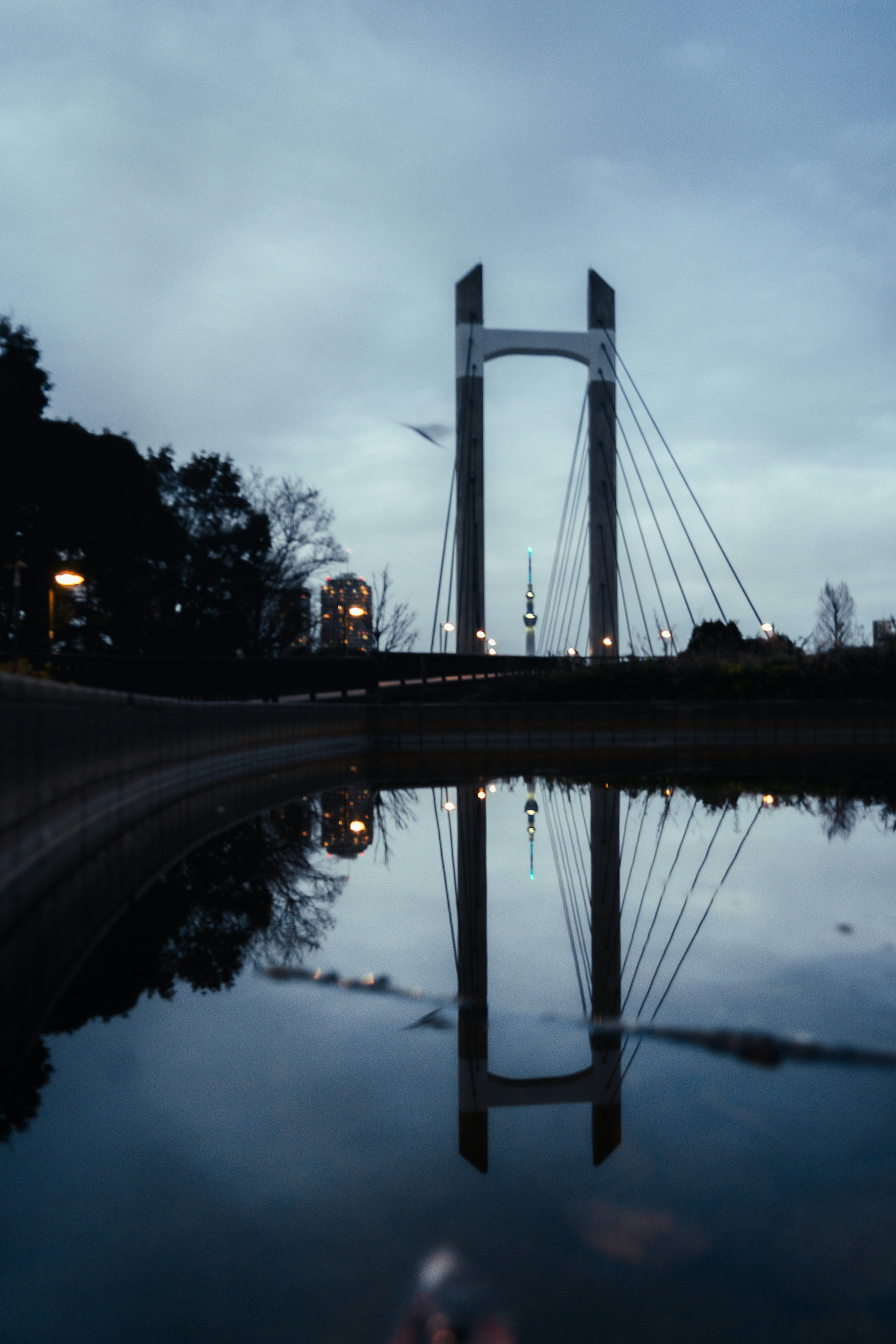 Reflection of a suspension bridge at dusk in calm water
