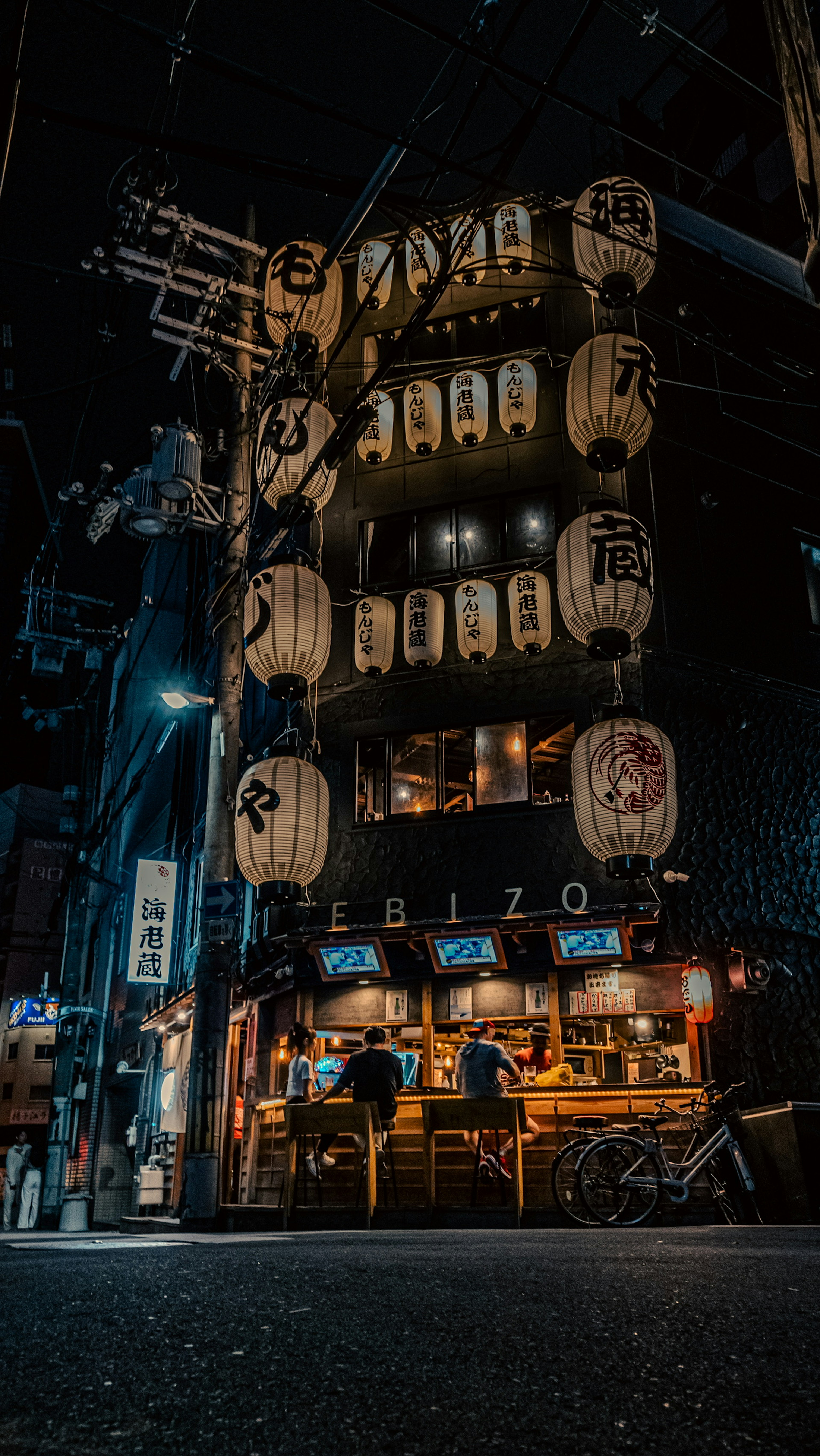 Calle nocturna con faroles y exterior de izakaya