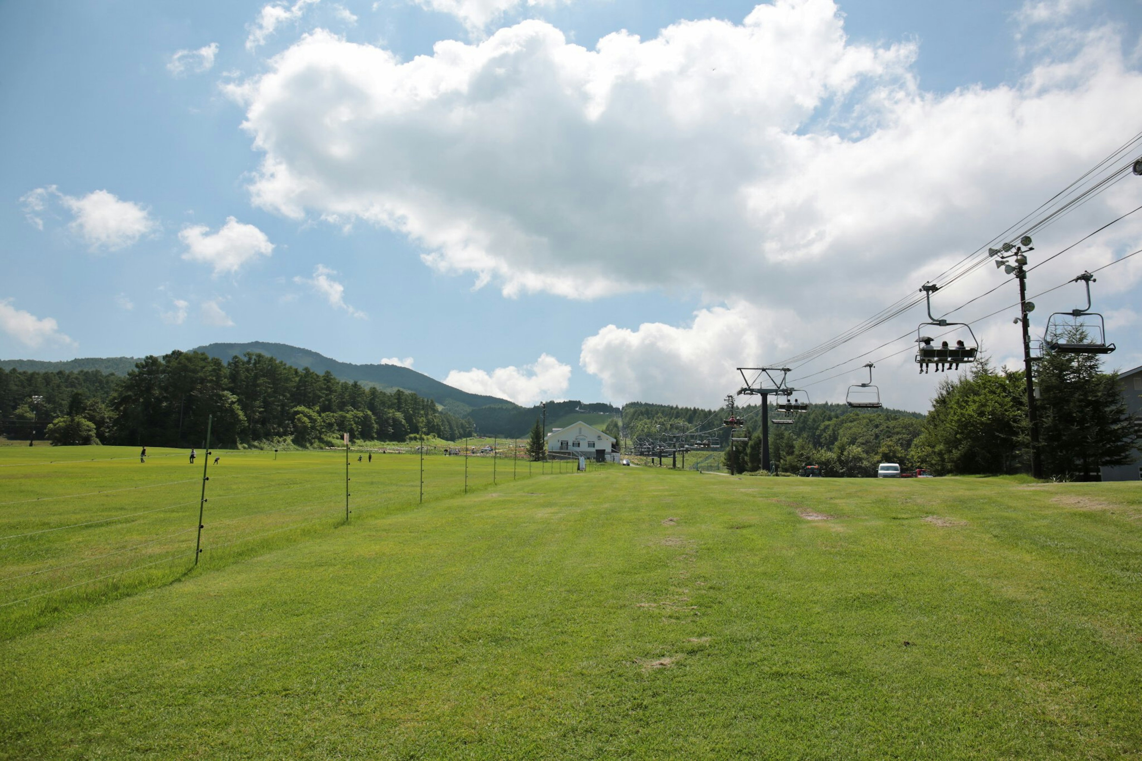 Vista panoramica di un prato verde con impianti di risalita e cielo blu