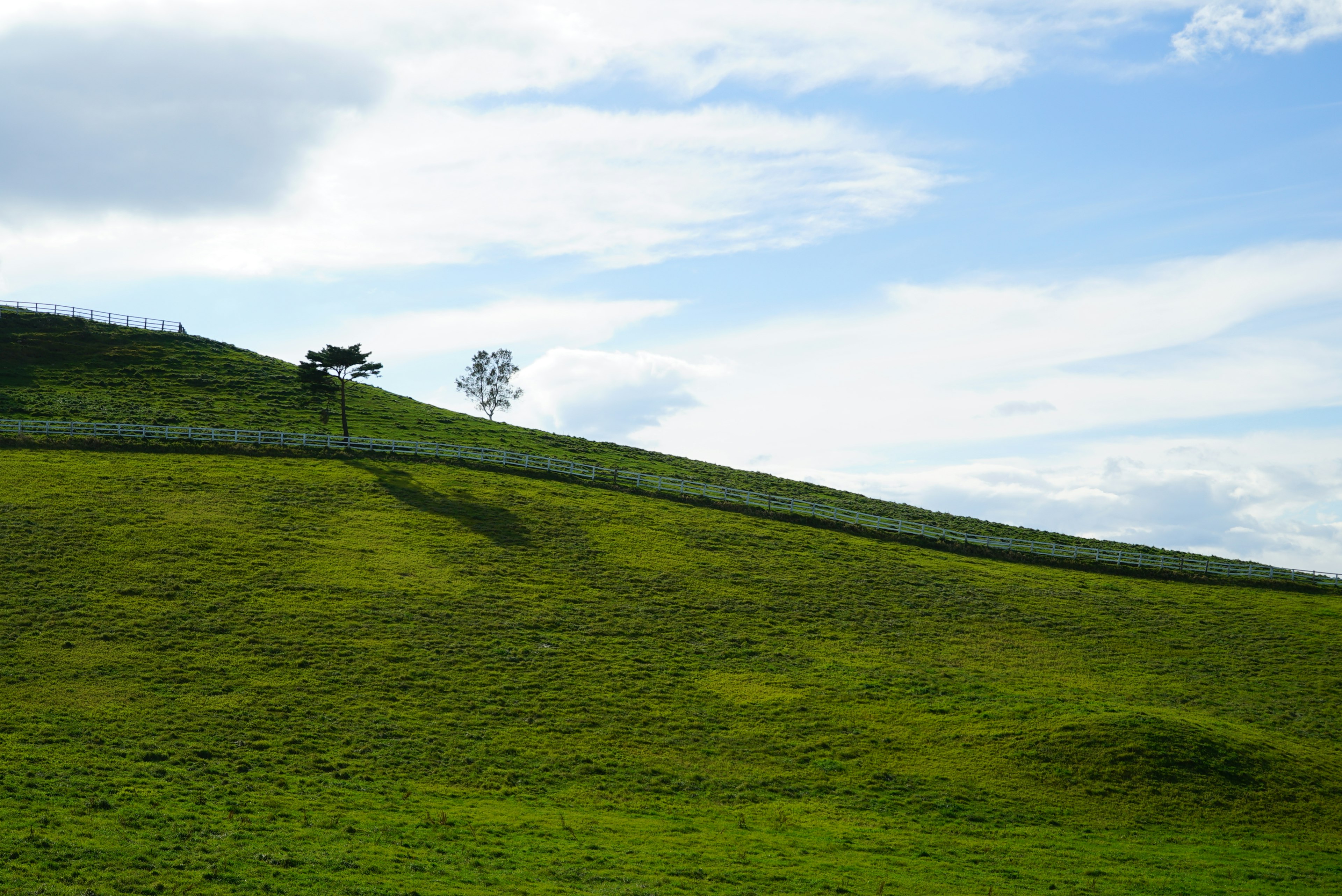 Collines verdoyantes sous un ciel bleu avec des nuages épars