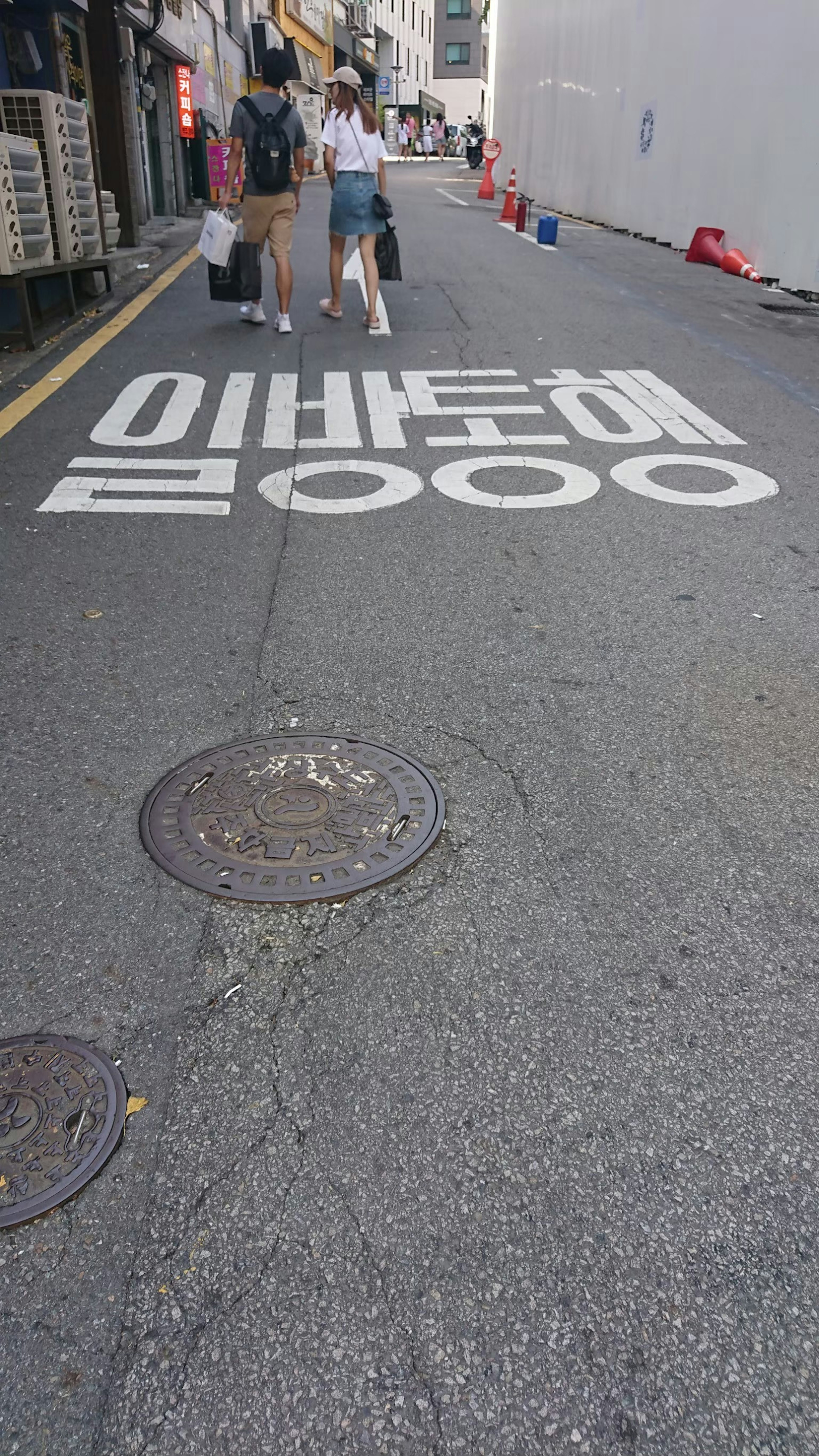 People standing on a street with Korean text painted on the pavement