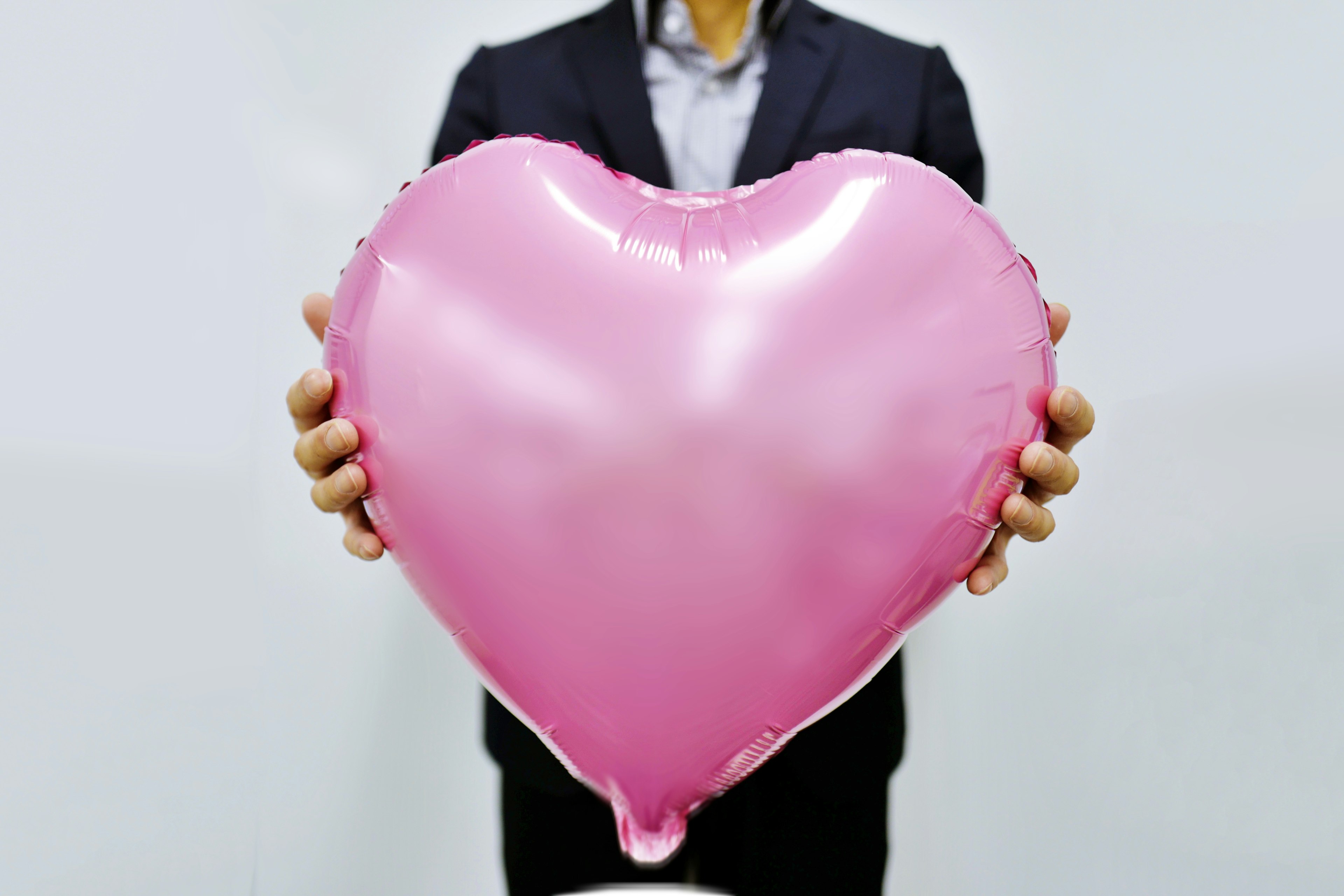 A man holding a pink heart-shaped balloon