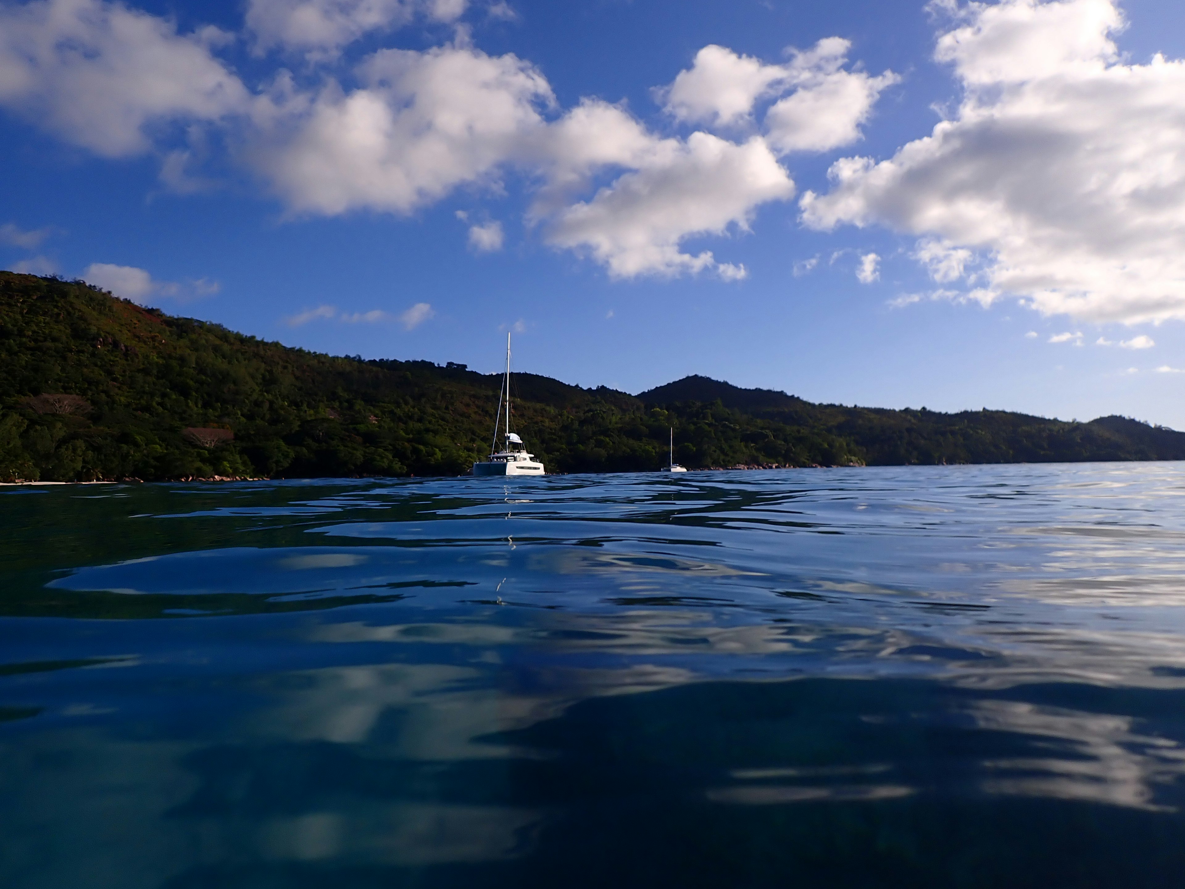 静かな海面に浮かぶヨットと美しい山々の風景