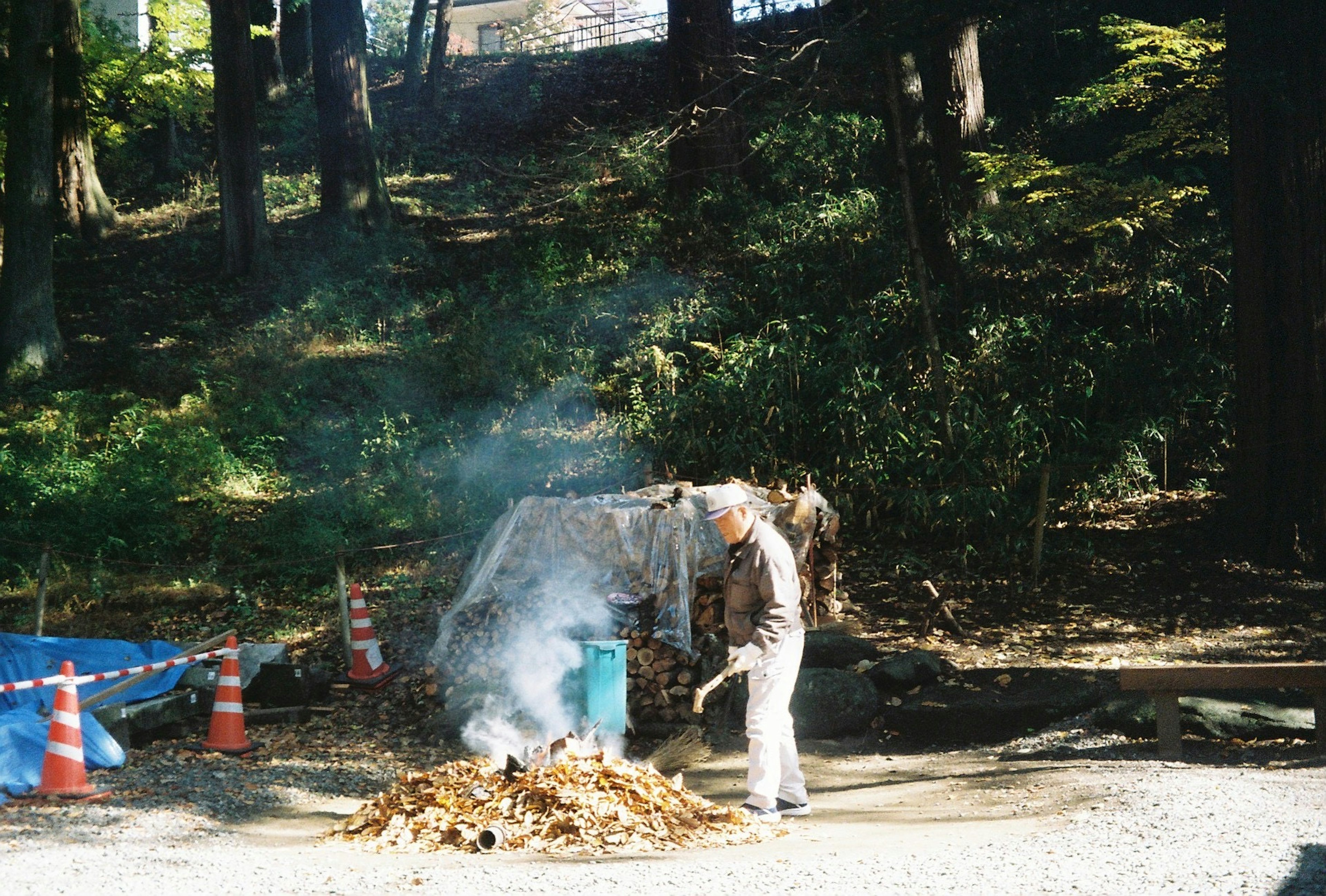 煙を上げている焼却中の落ち葉と作業員