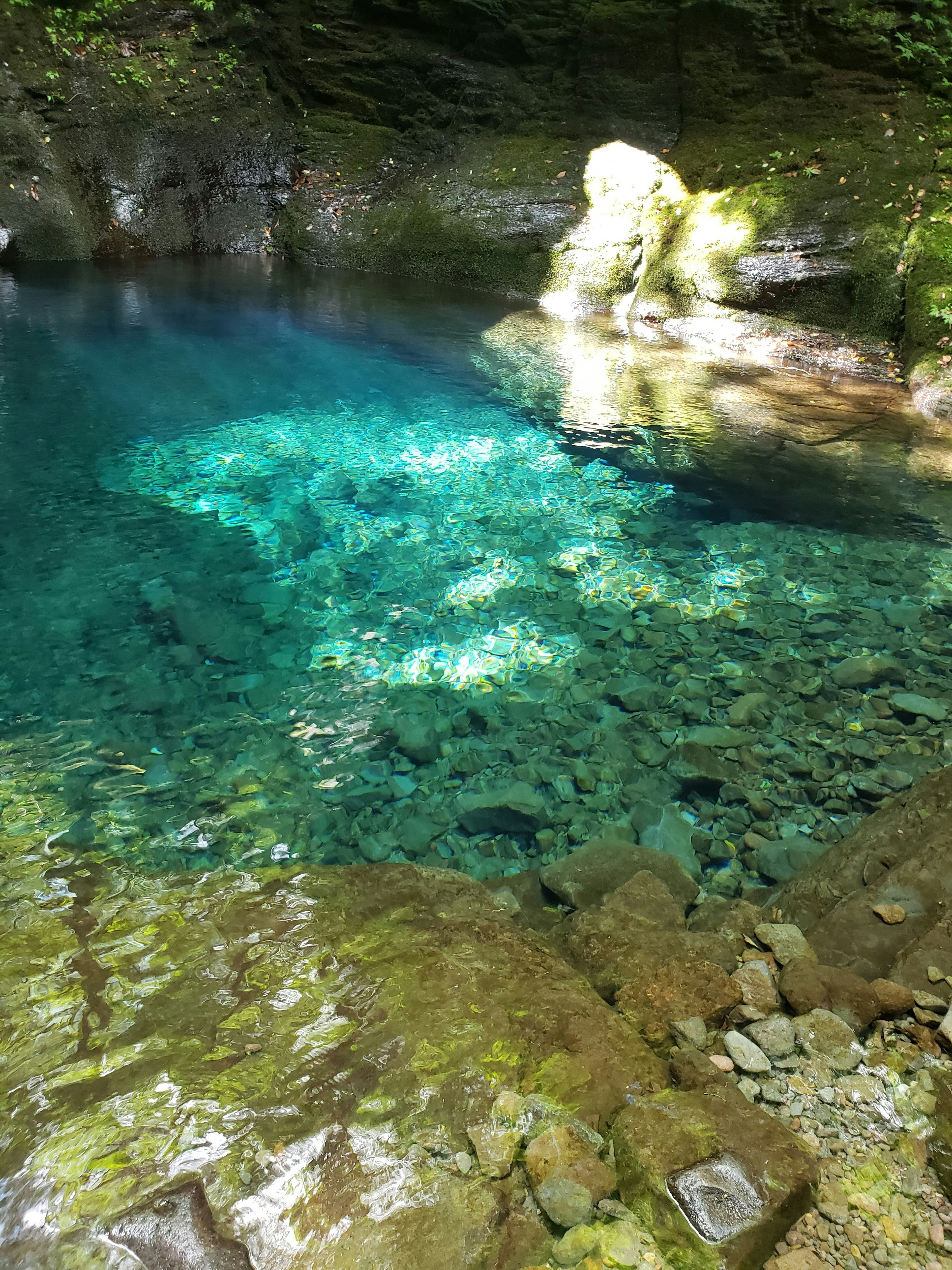 Clear blue water pool surrounded by mossy rocks