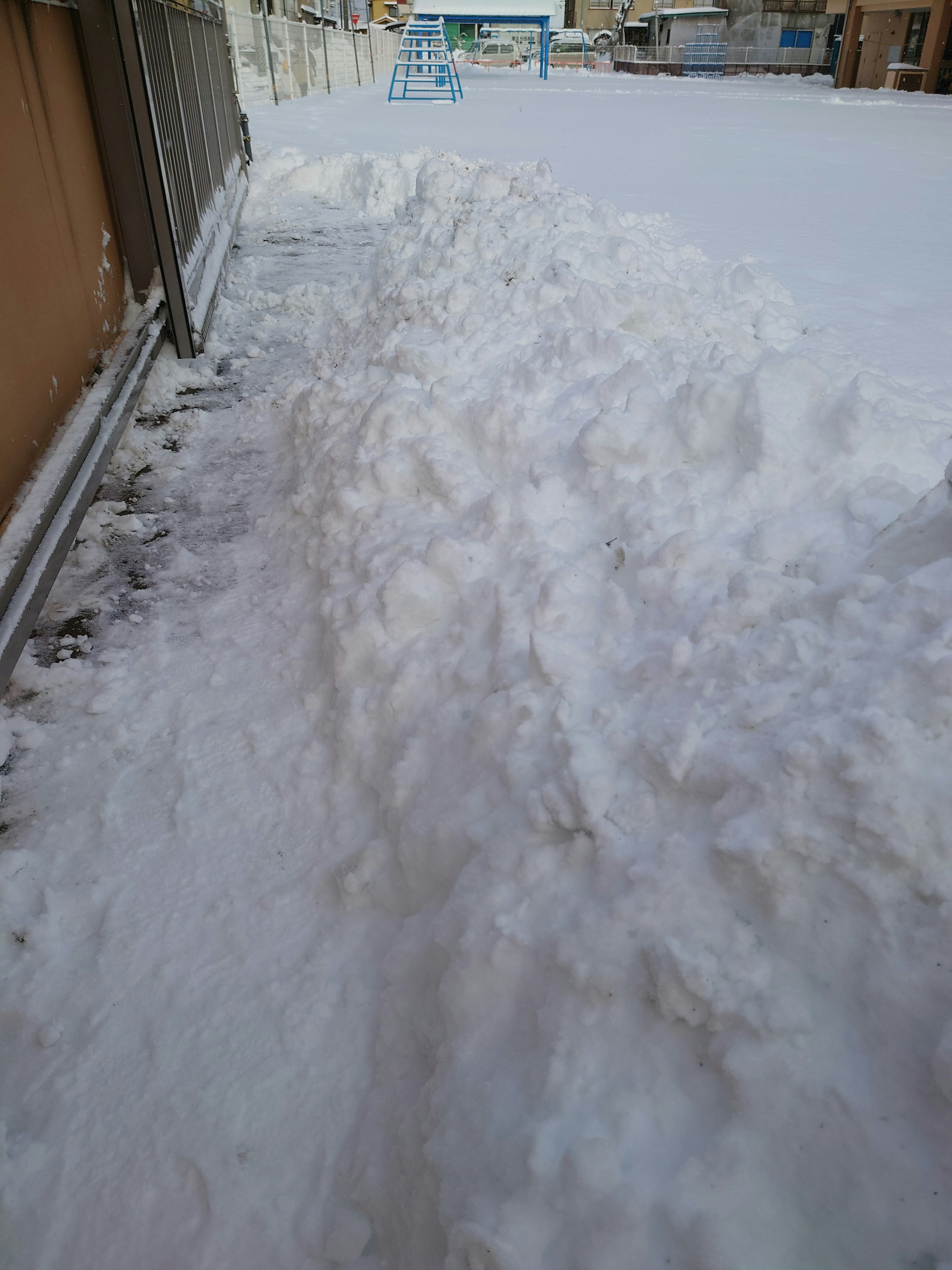 Snow-covered sidewalk with large snowdrifts alongside