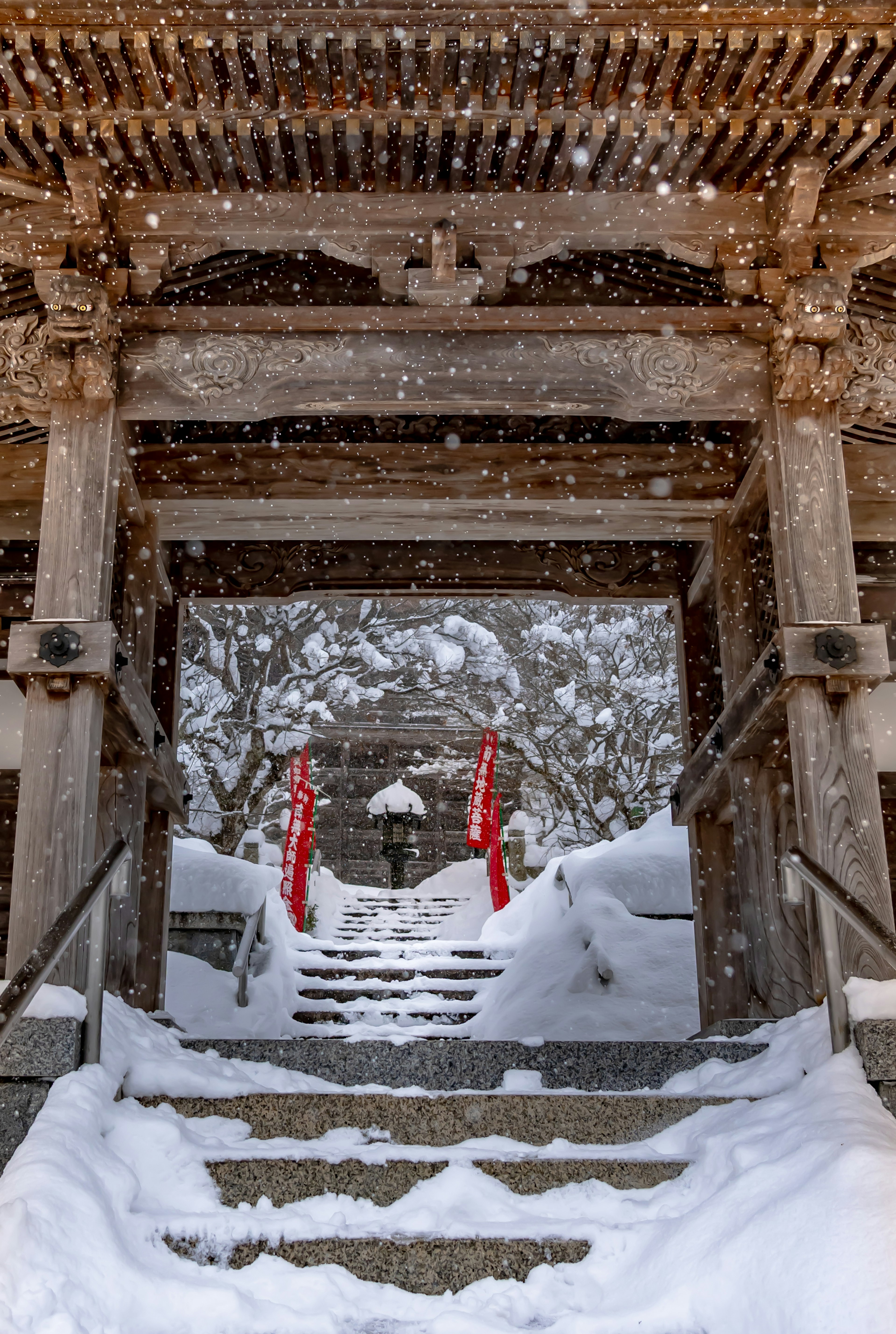 Escaleras cubiertas de nieve que llevan a la entrada de un santuario adornada con tela roja