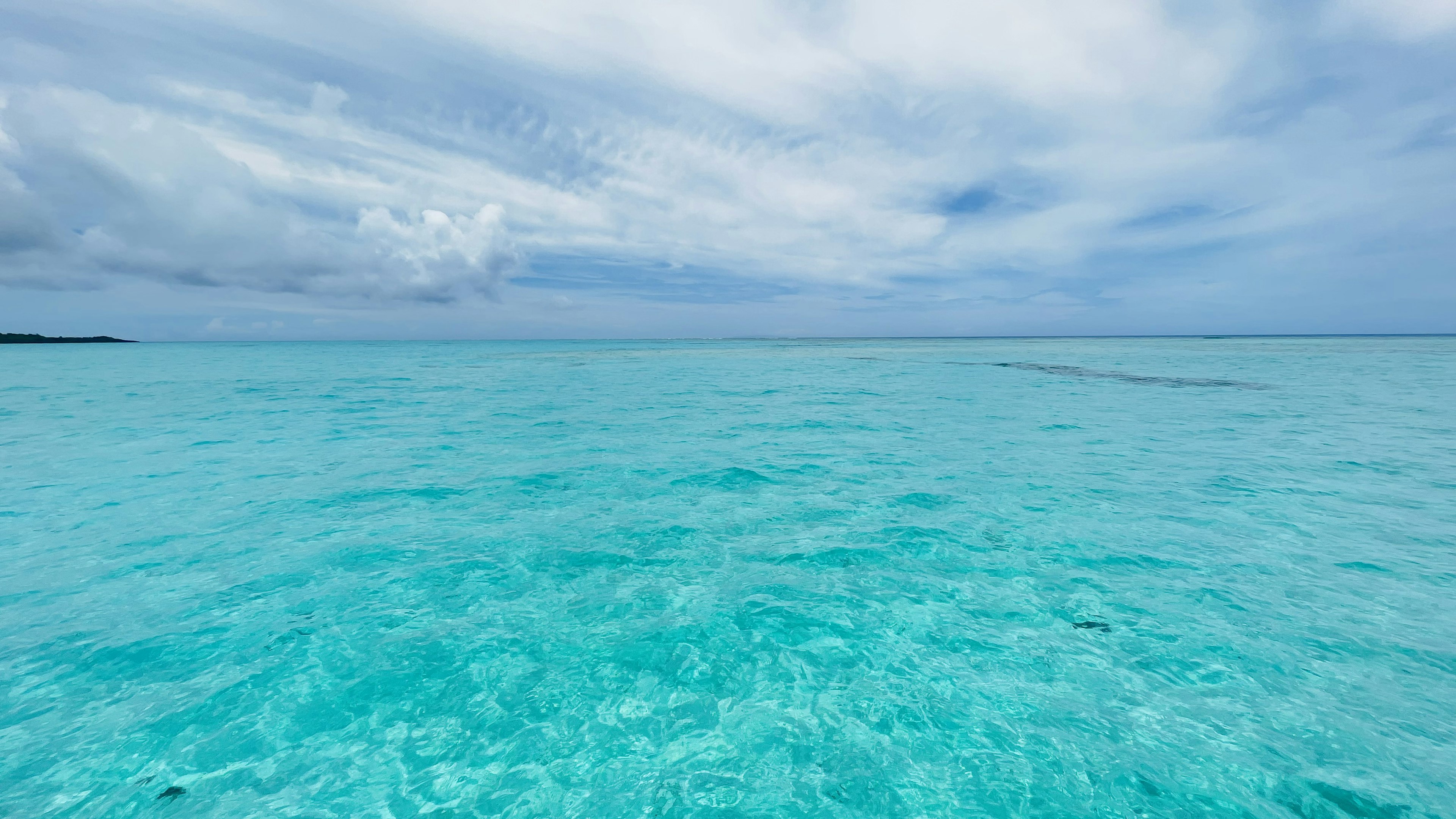 Vast turquoise ocean under a cloudy sky