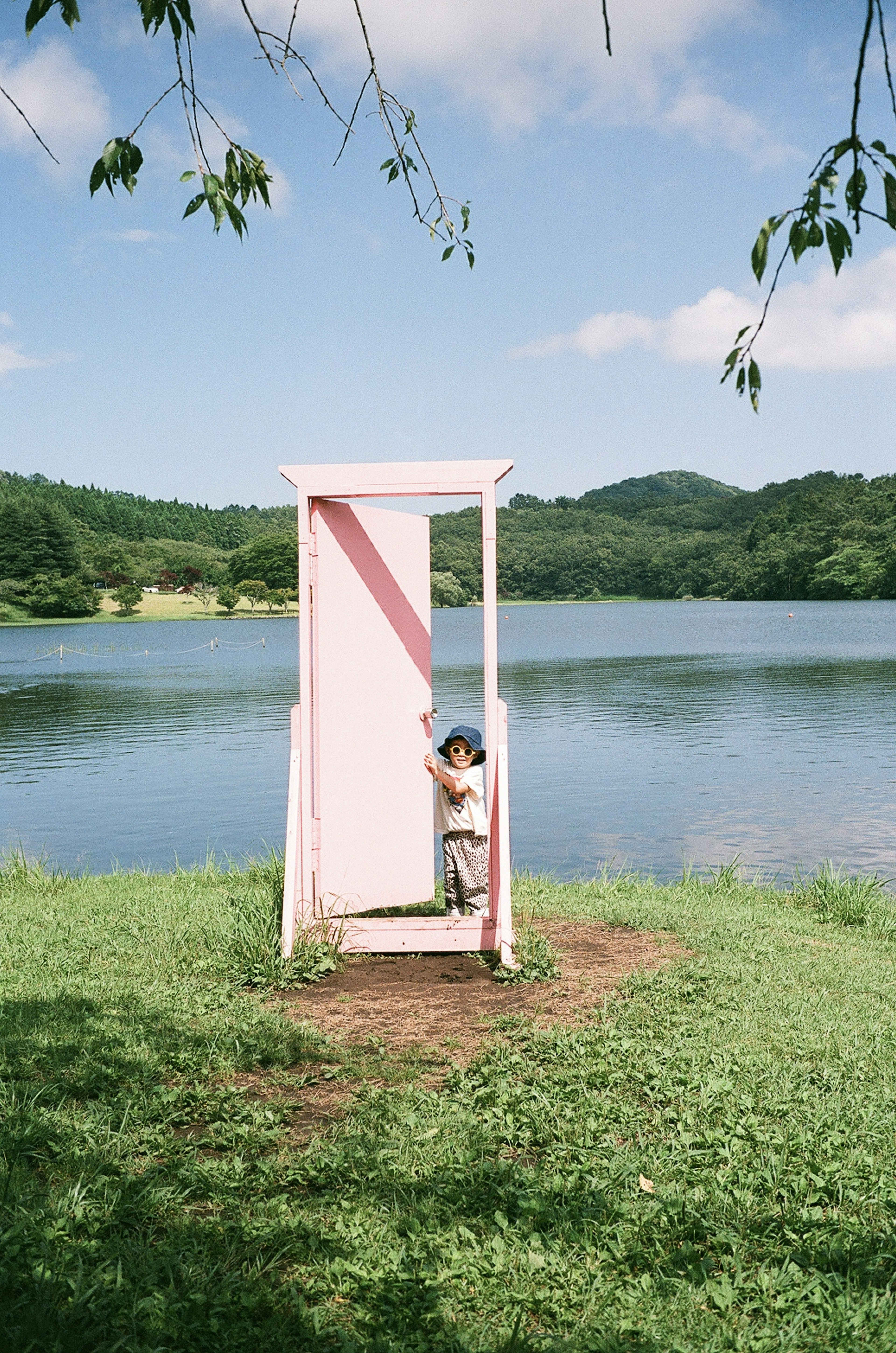 湖の近くにあるピンクのドアの前に立つ子供