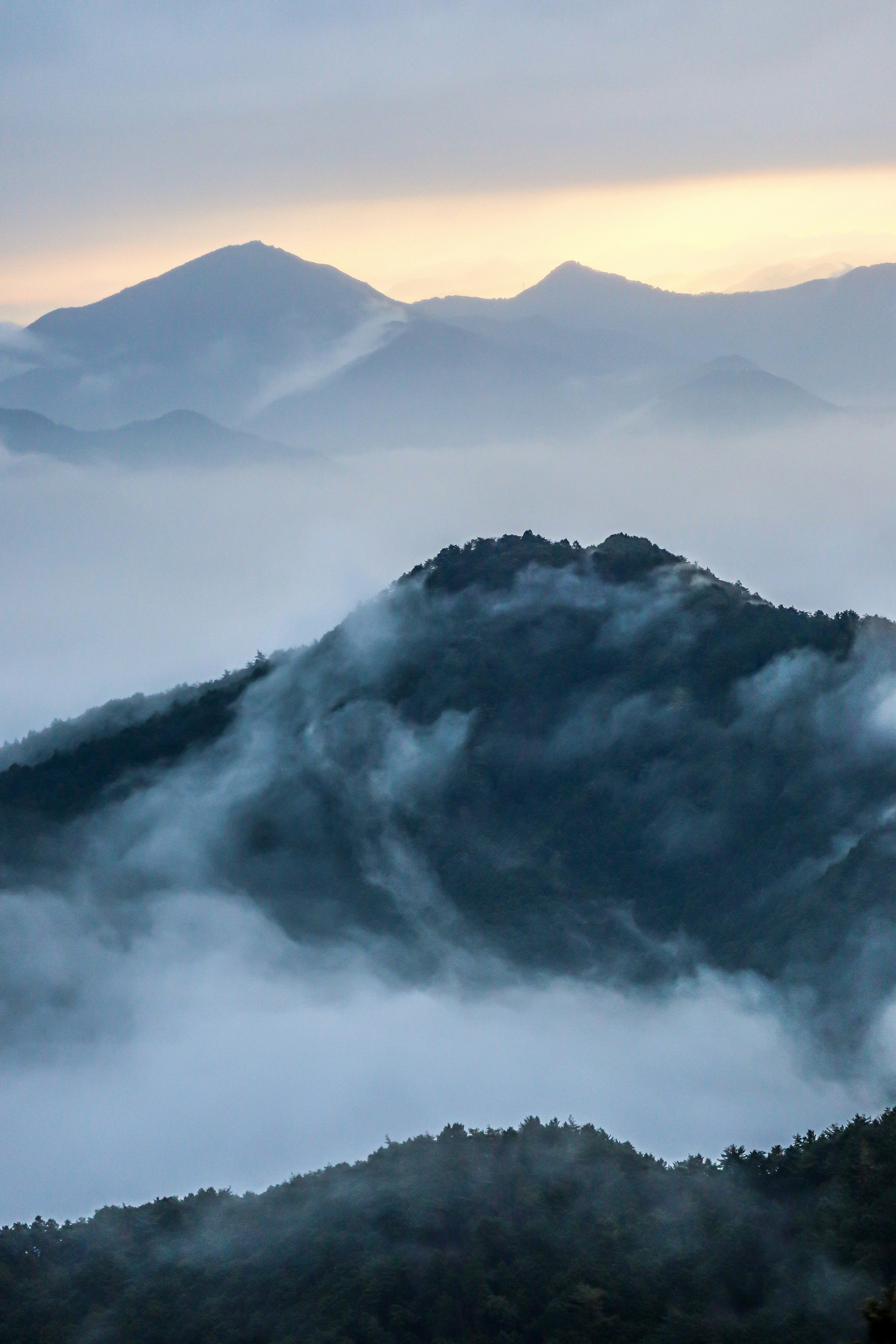 Paesaggio montano avvolto nella nebbia con un cielo all'alba