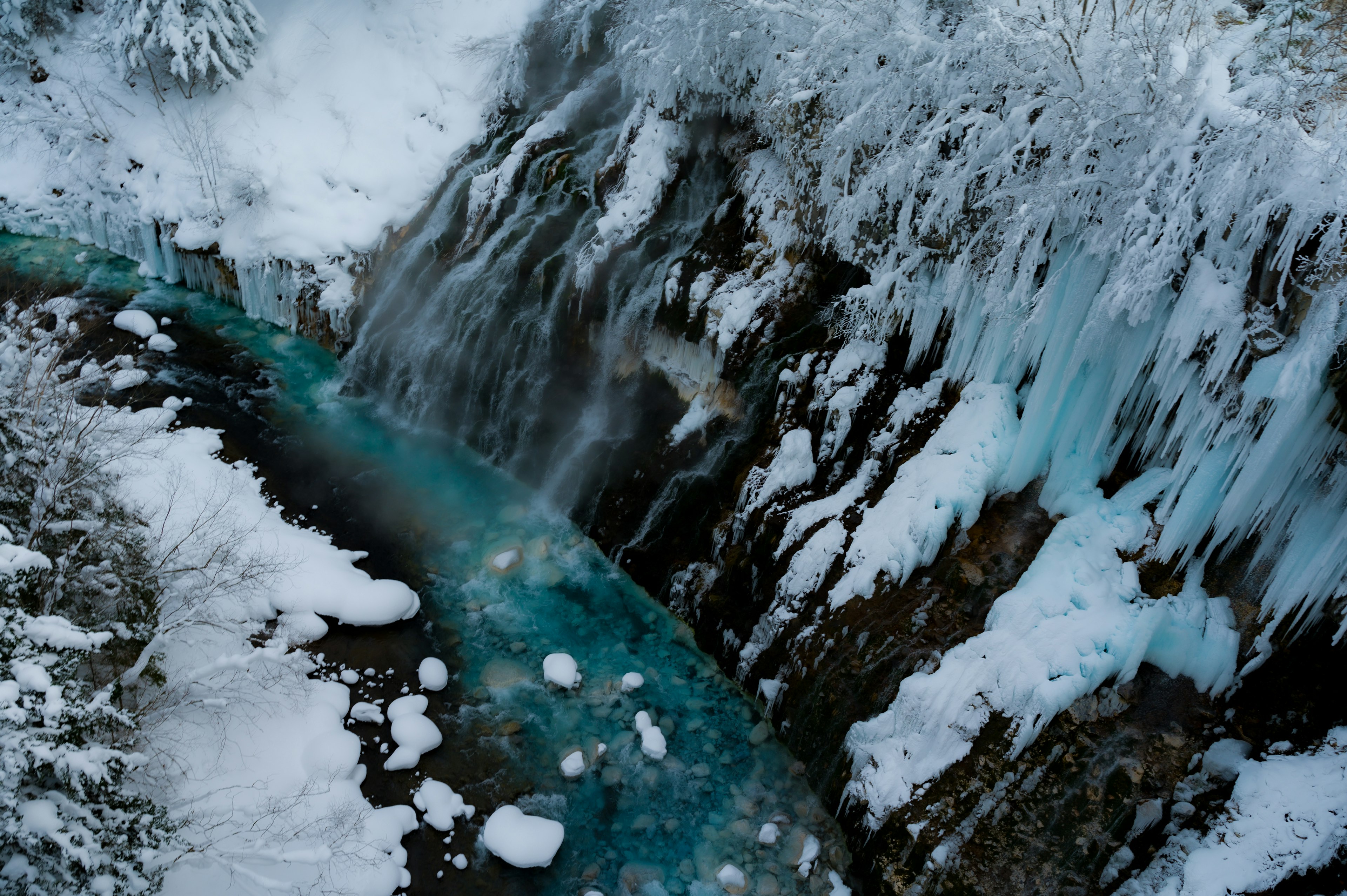 Gefrorener Bach umgeben von Schnee und Eisformationen