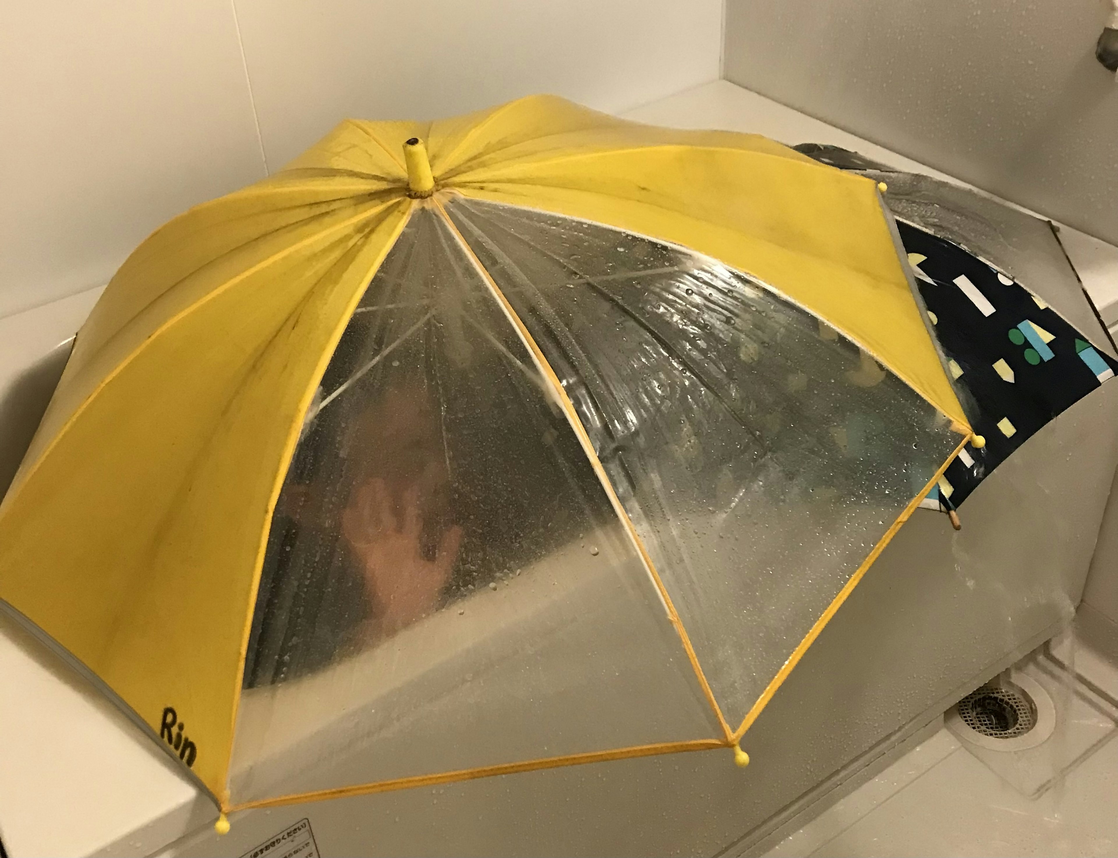 A yellow and clear umbrella placed over a sink