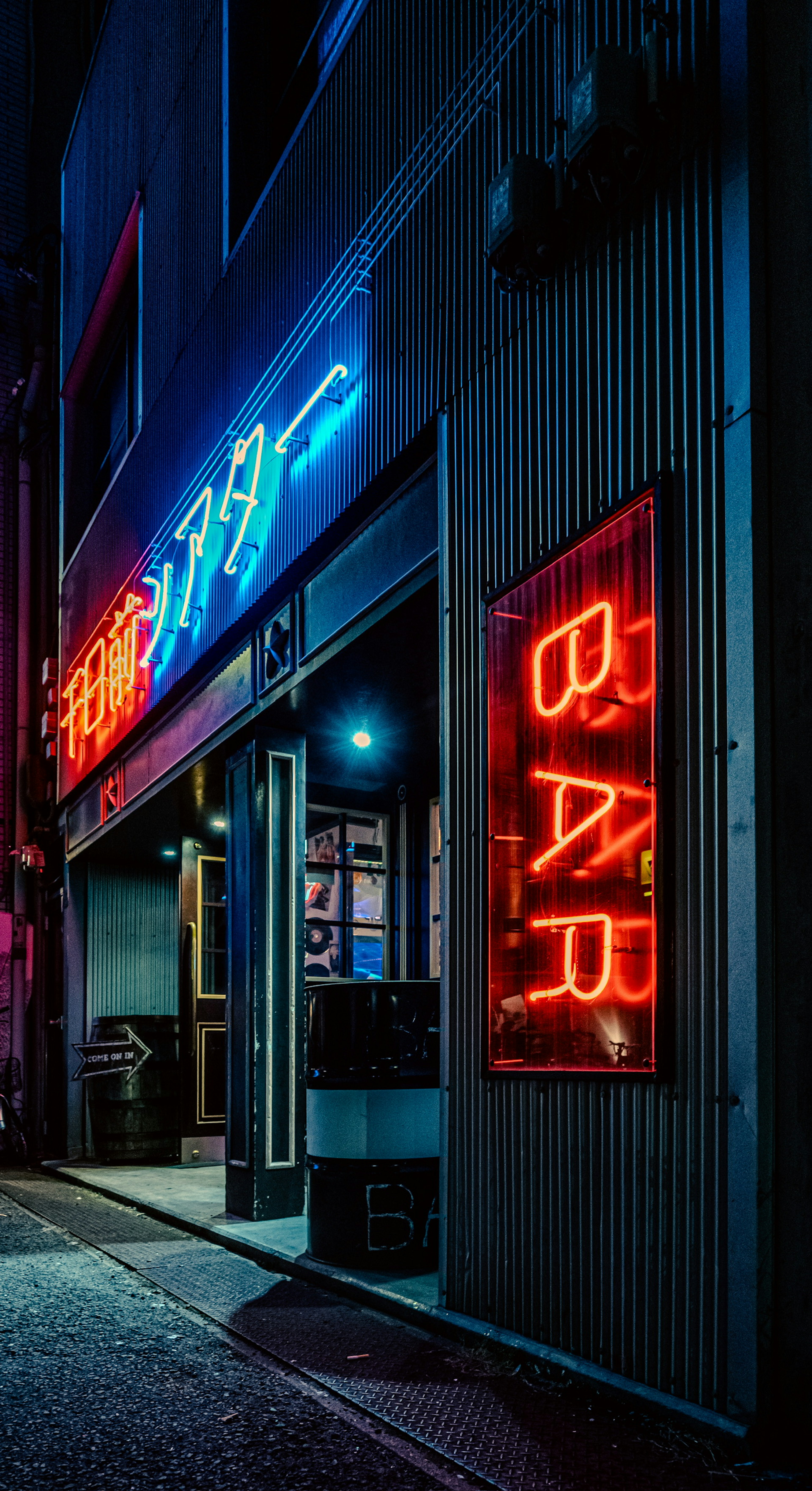 Entrée d'un bar illuminée par des enseignes au néon et des lumières bleues