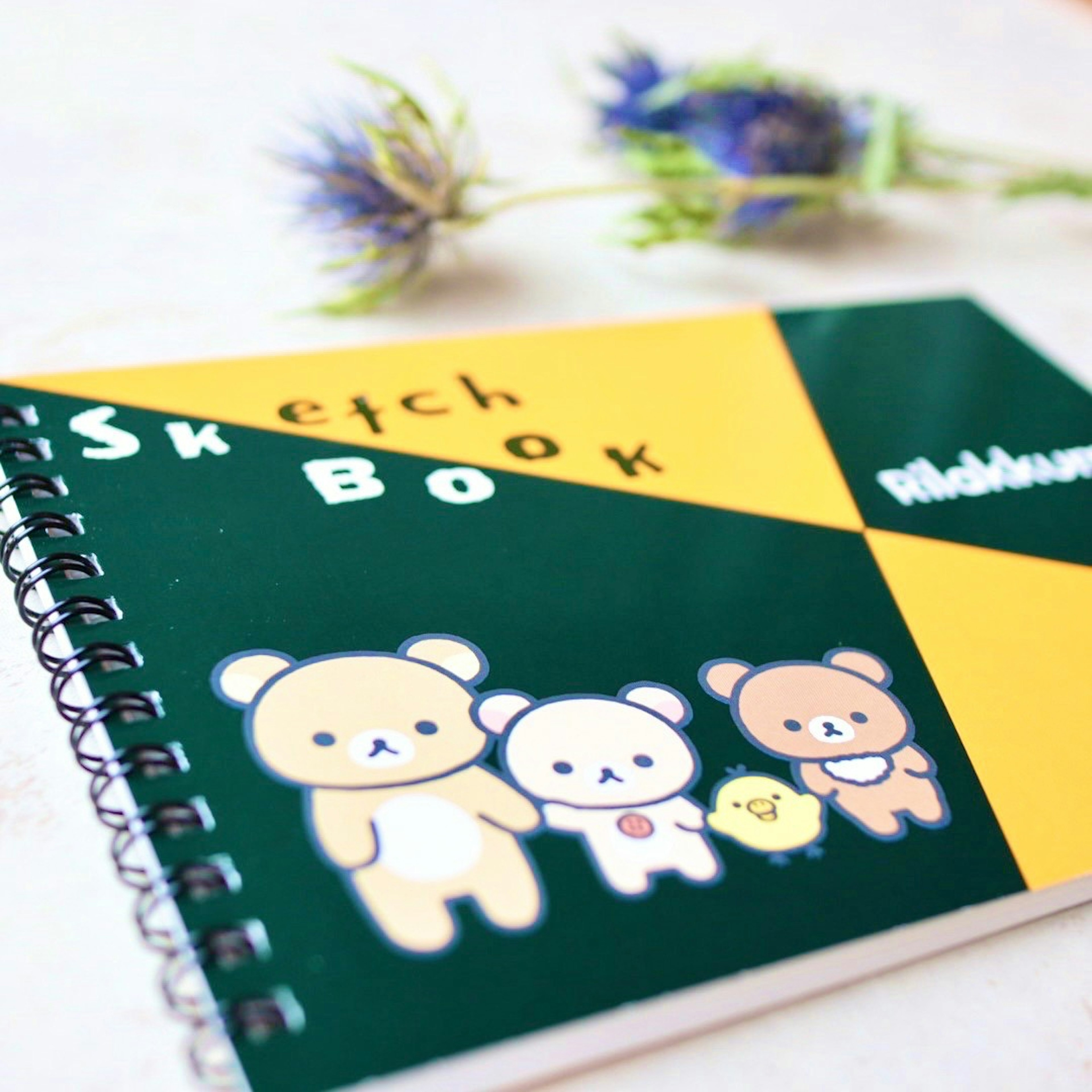 Un cuaderno de bocetos con una cubierta verde y amarilla que presenta personajes de dibujos animados adorables