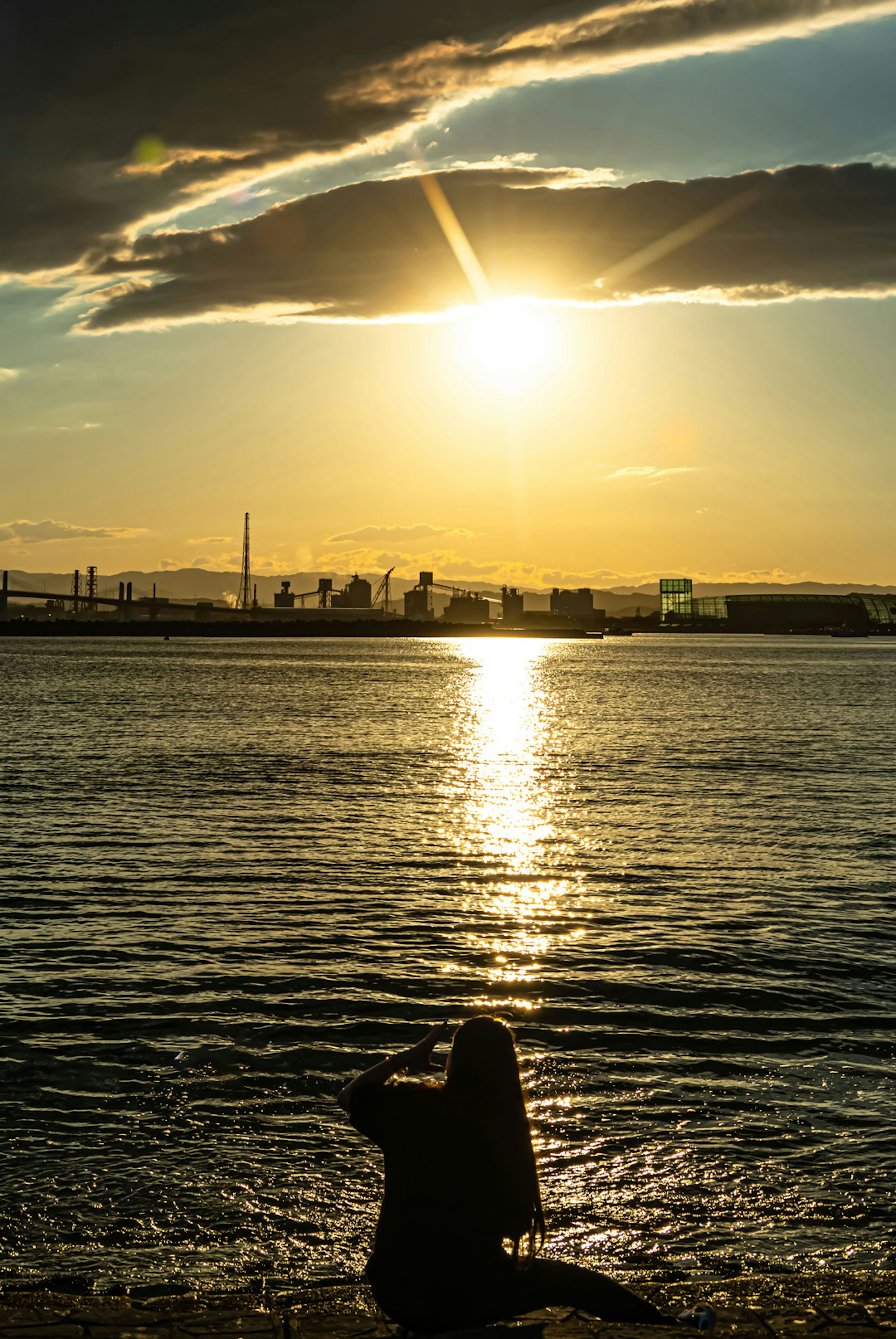 Schatten einer Person, die auf das Meer schaut mit Sonnenuntergang und Spiegelung im Wasser