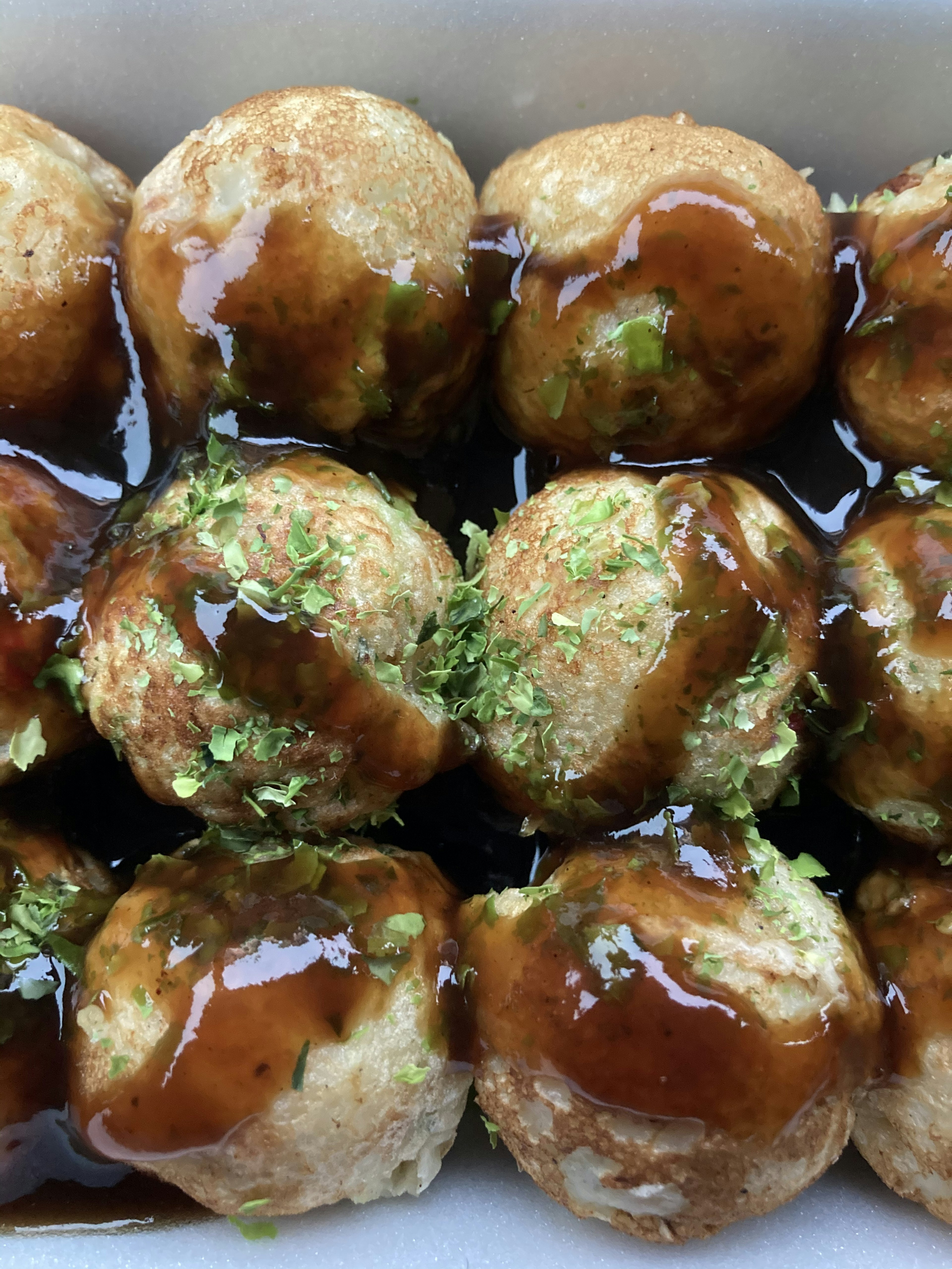 Deliciosos takoyaki cubiertos con salsa y copos de algas verdes