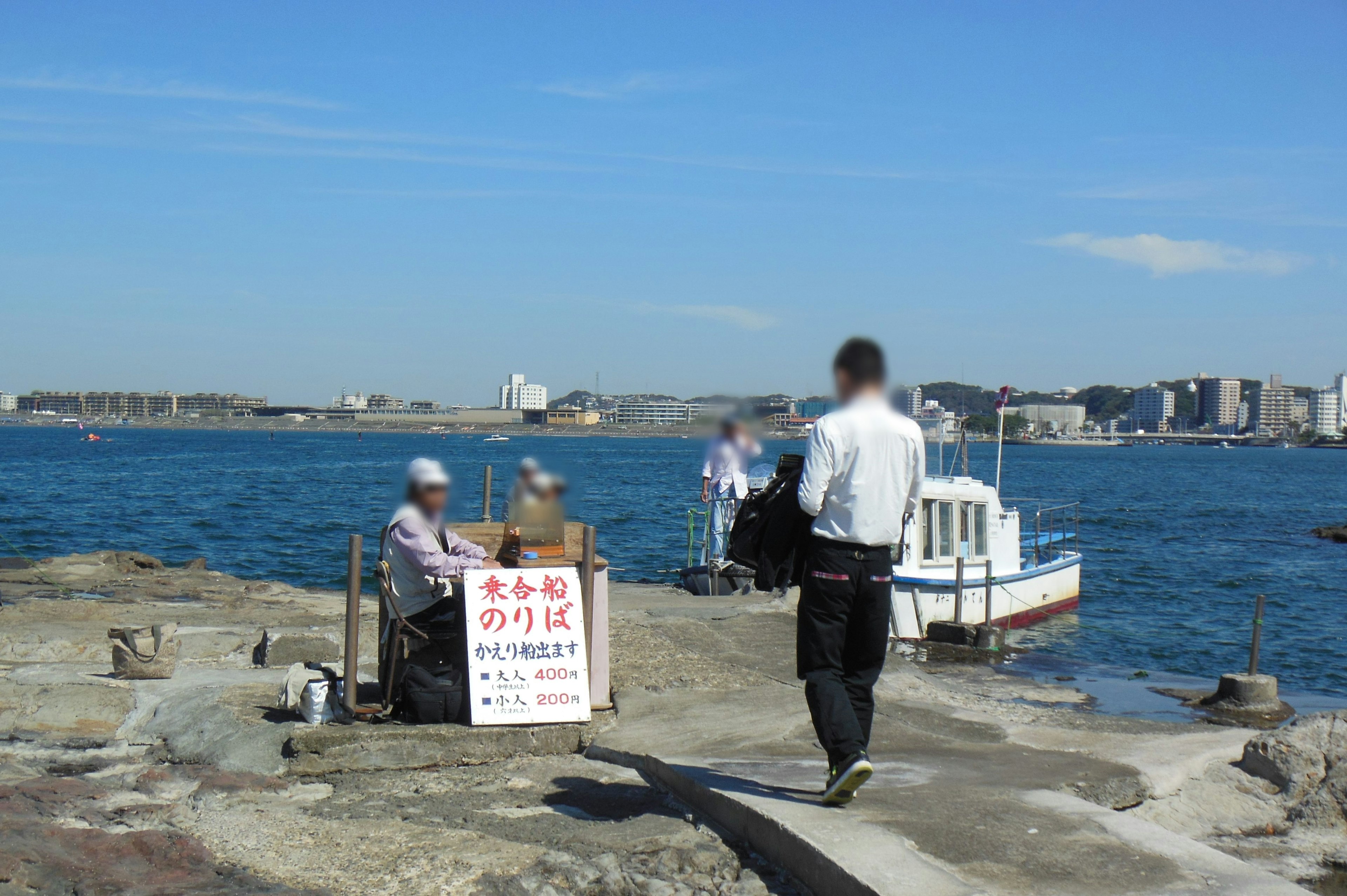 港の桟橋で魚を売る二人の男性と船を背景にした風景