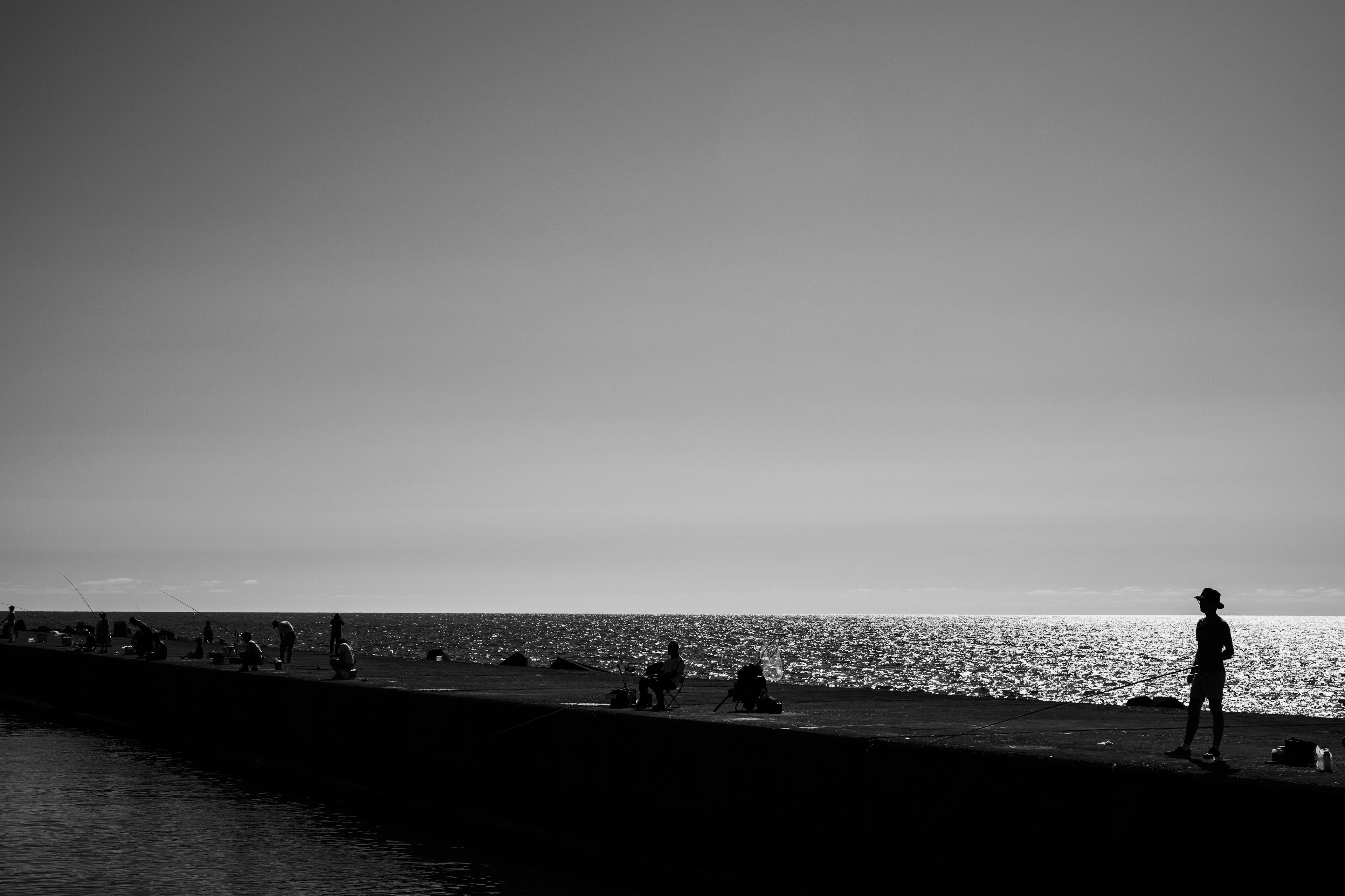 Silhouette di persone lungo una costa con un mare calmo