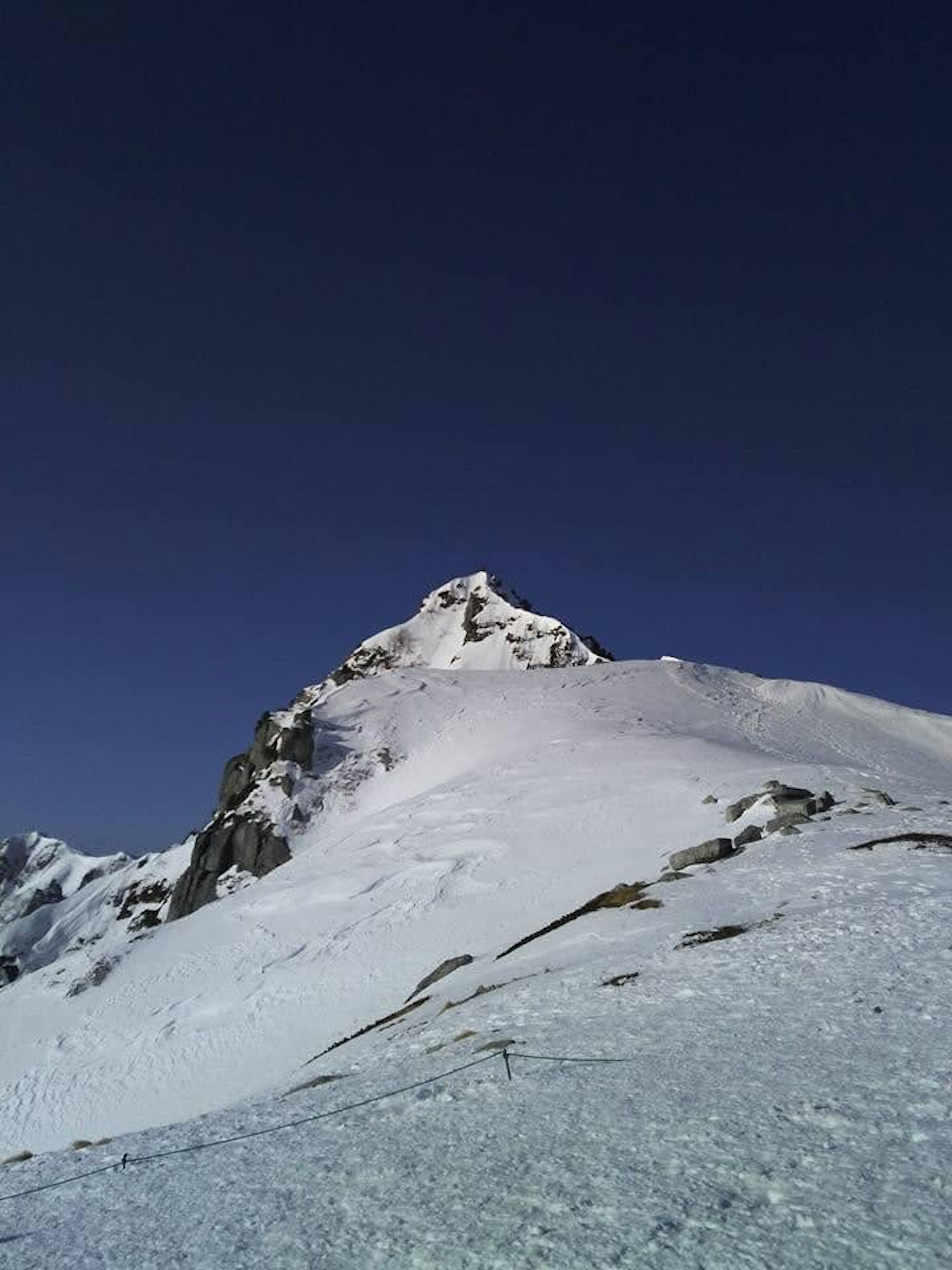 Sommet d'une montagne recouvert de neige sous un ciel bleu clair