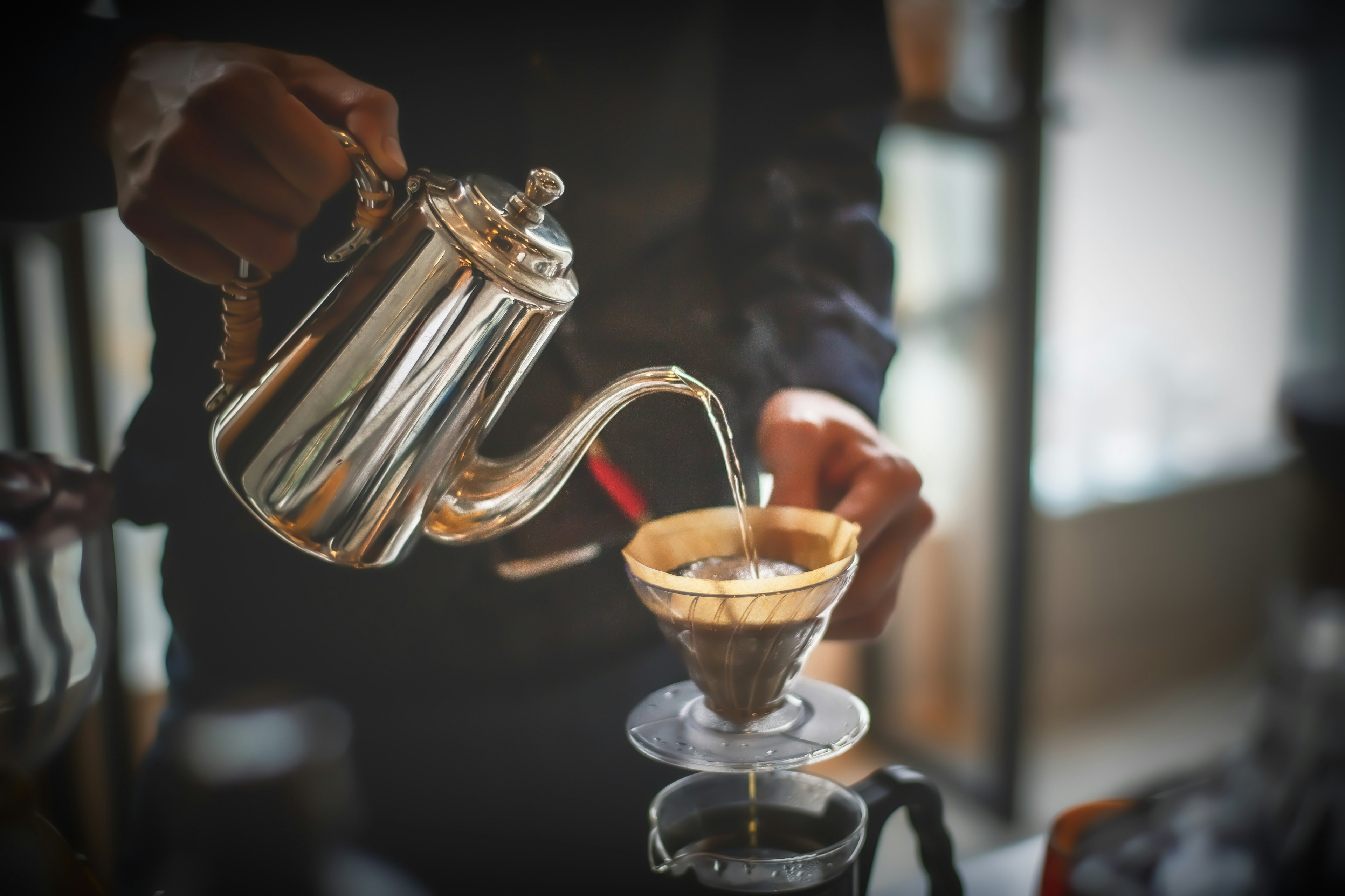 Silver kettle pouring coffee into a dripper