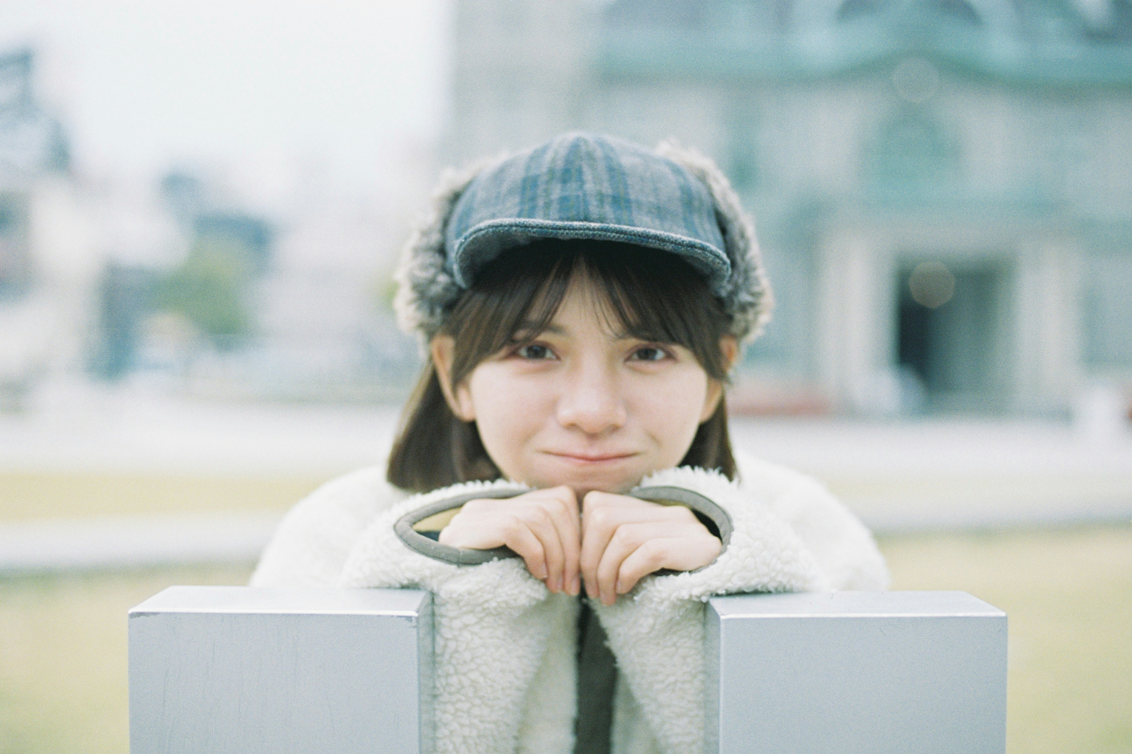 Una joven con una gorra gris sonriendo suavemente