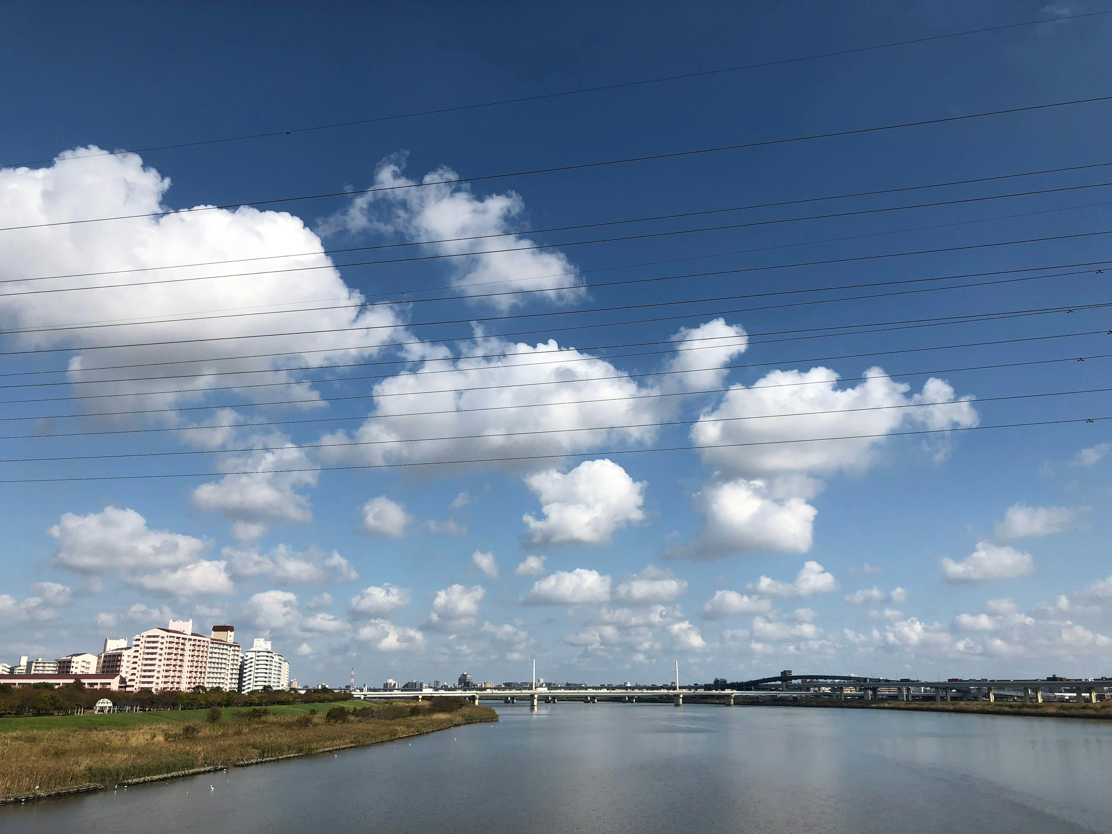 Vista panoramica di un fiume sotto un cielo blu con nuvole bianche soffici e grattacieli nelle vicinanze