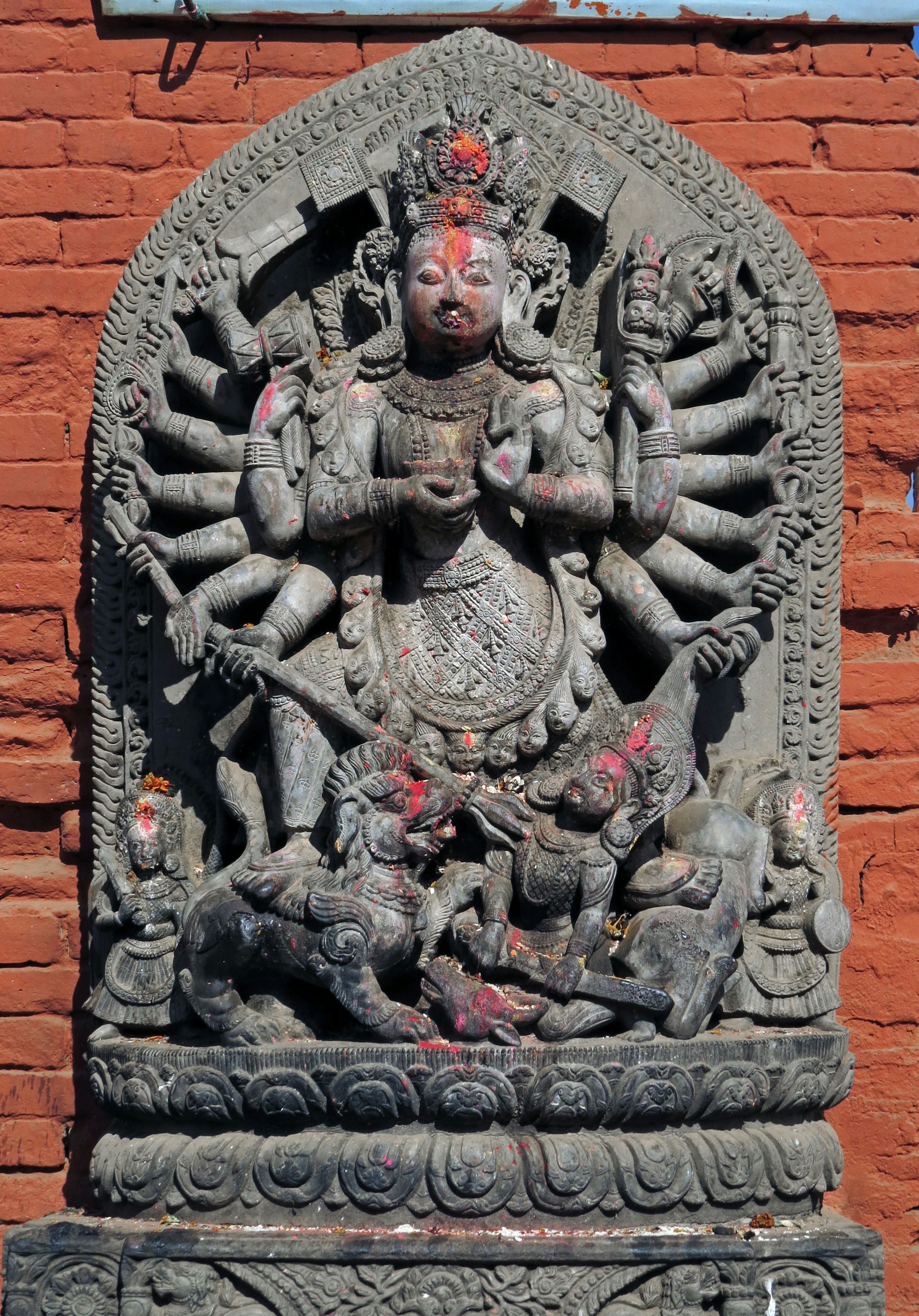 A multi-armed goddess statue in front of a red wall