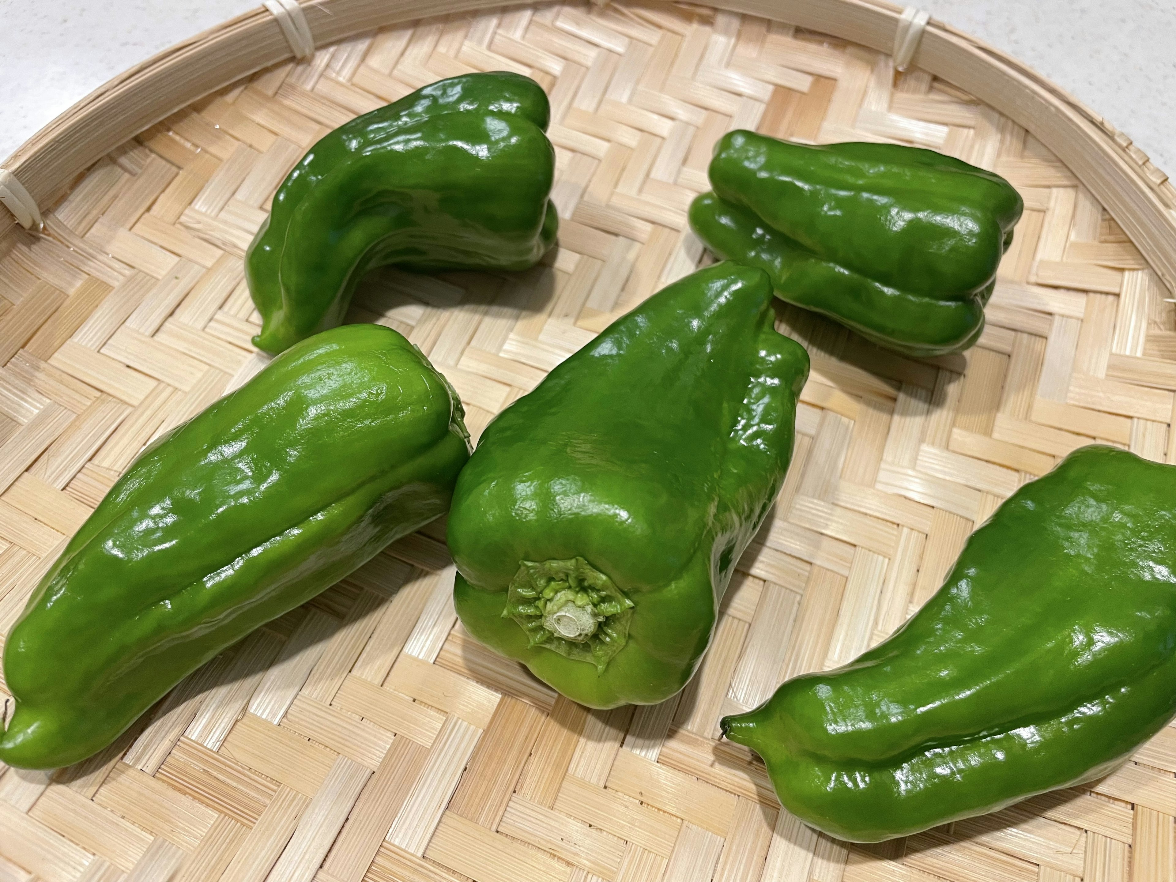 Green bell peppers arranged on a woven basket